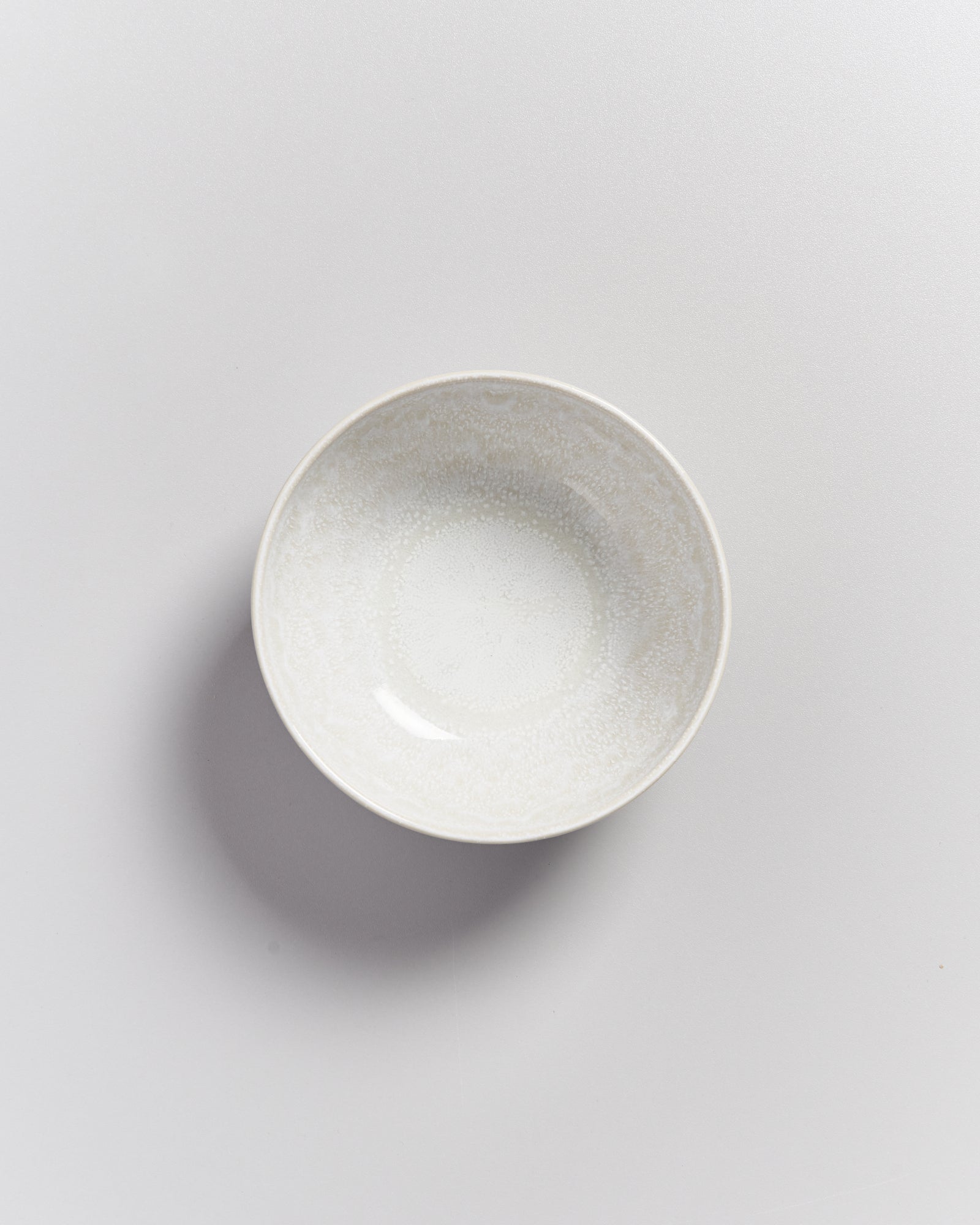 Weiße Porzellanschüssel auf hellgrauem Hintergrund, von oben fotografiert.