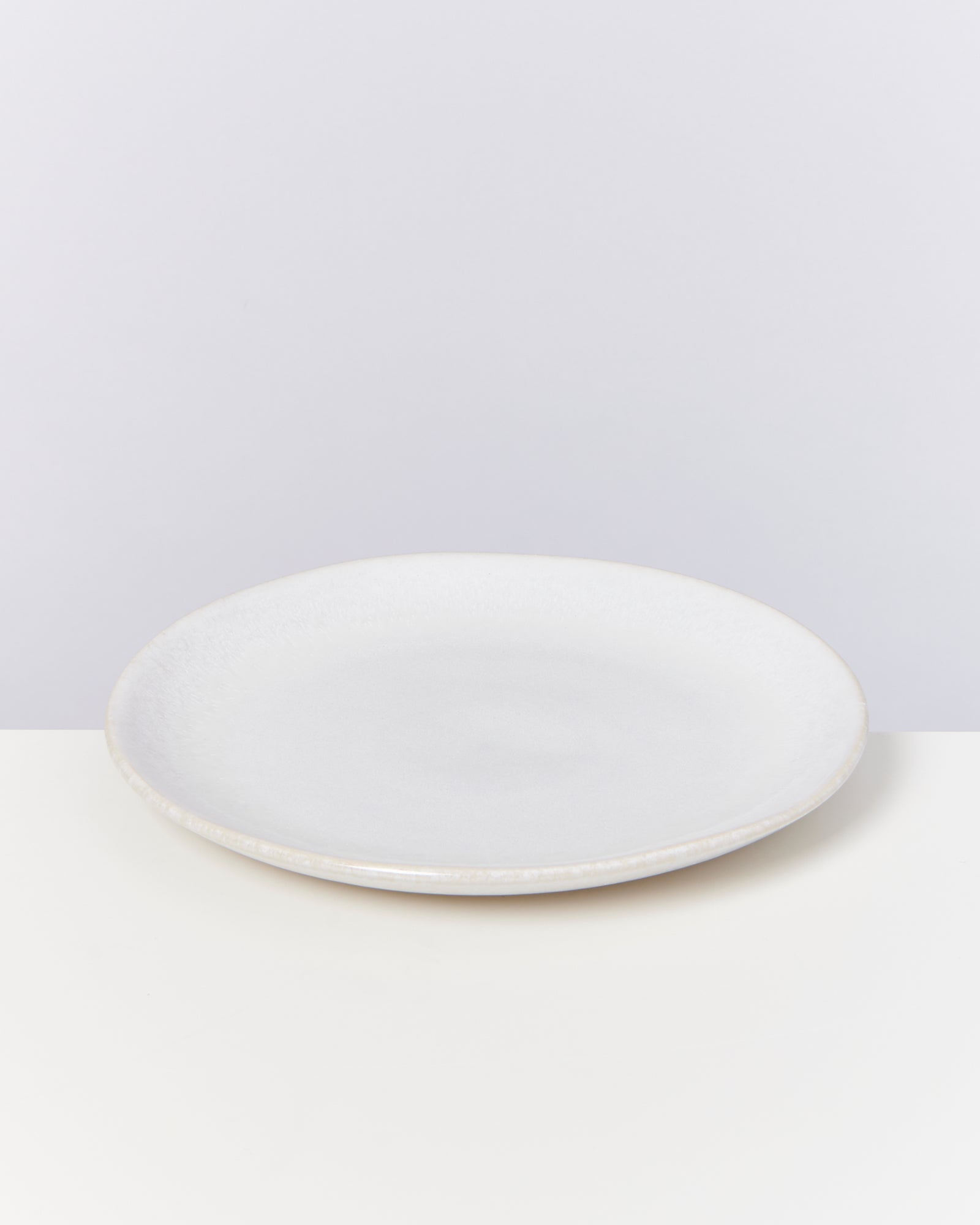 Ein weißer, runder Teller auf einem hellen Hintergrund.