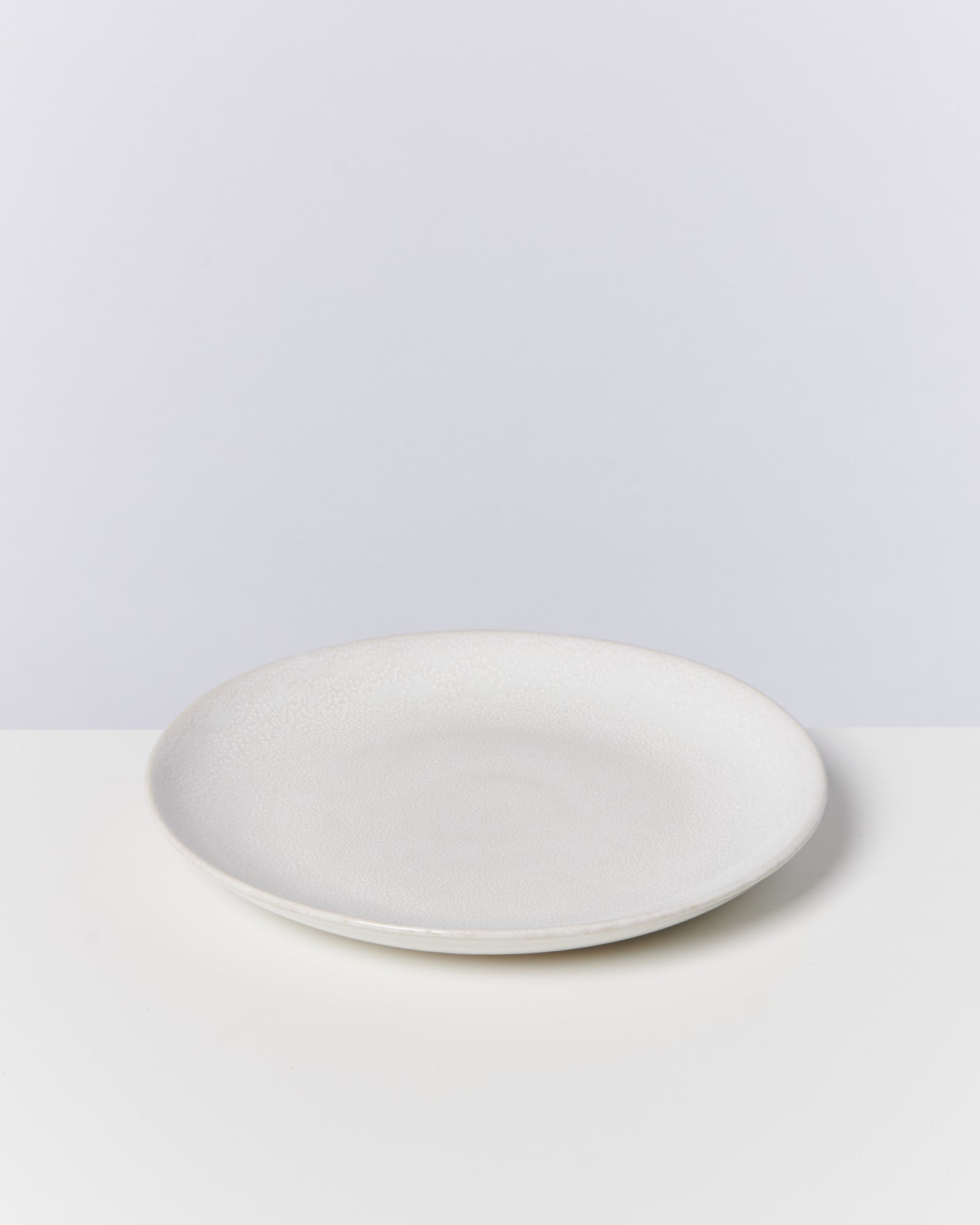 Ein einfacher, weißer Teller auf einem weißen Hintergrund.