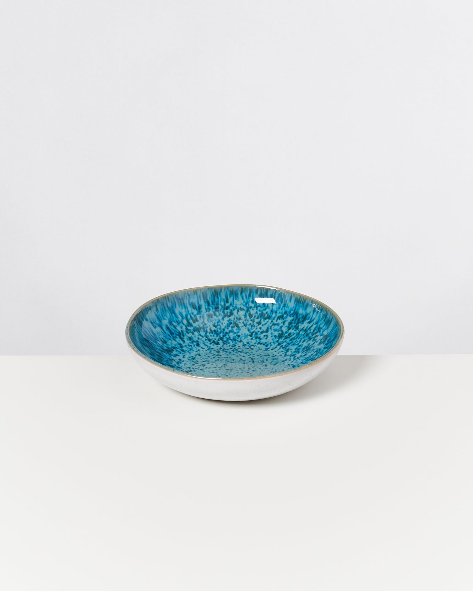 Keramikschale mit blauem, gesprenkeltem Innenmuster auf einem weißen Hintergrund.