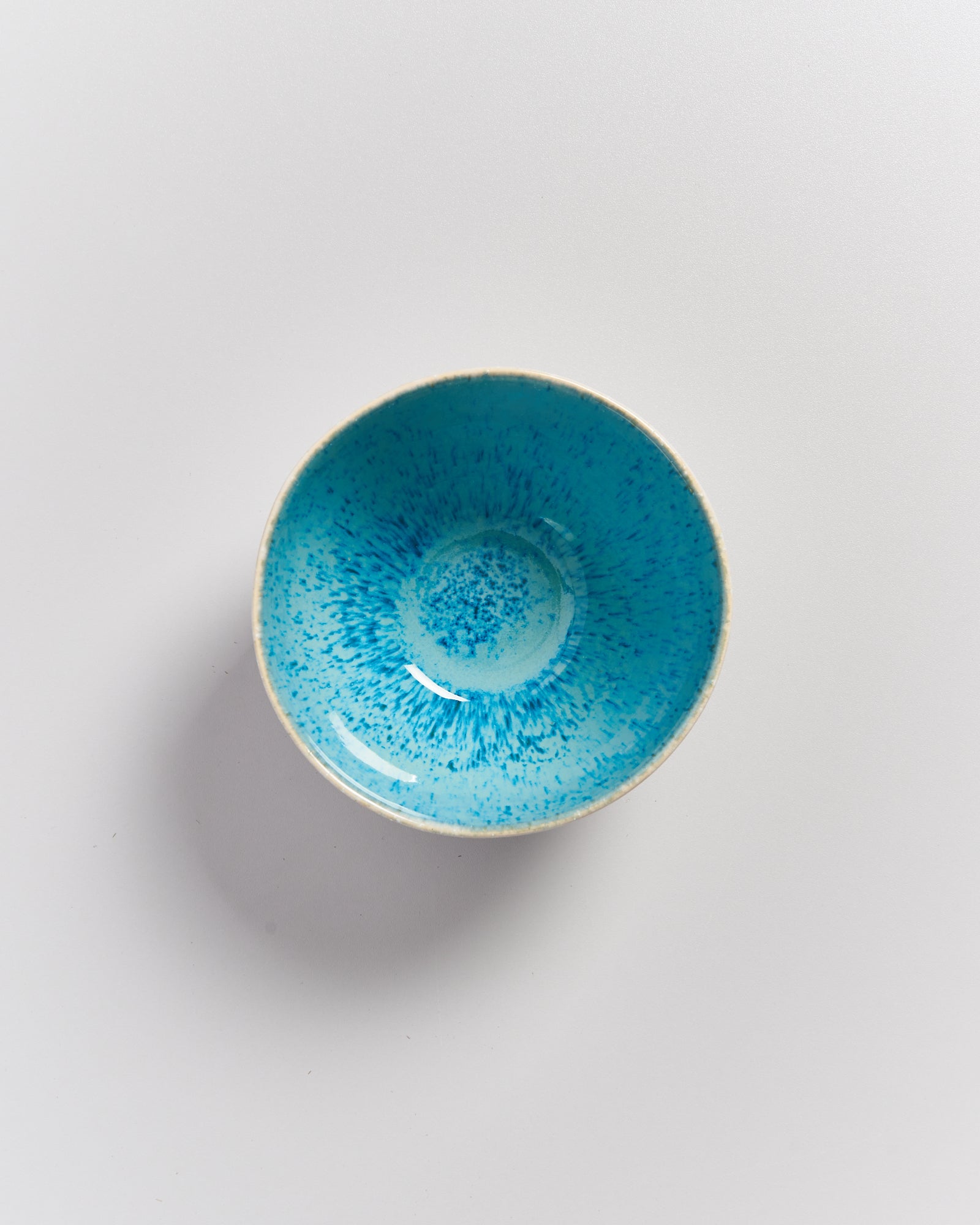 Eine blaue Schüssel mit gesprenkeltem Muster auf weißem Hintergrund.