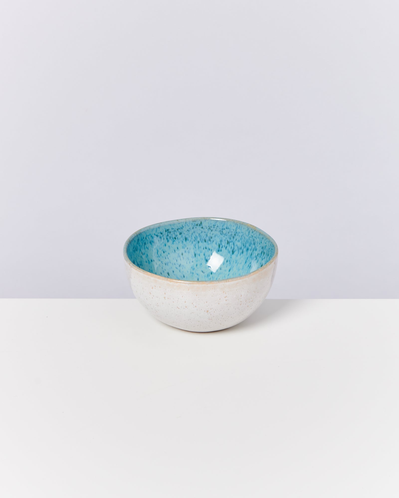 Keramikschale mit blauer, gesprenkelter Innenfläche und weißer Außenseite auf weißem Hintergrund.