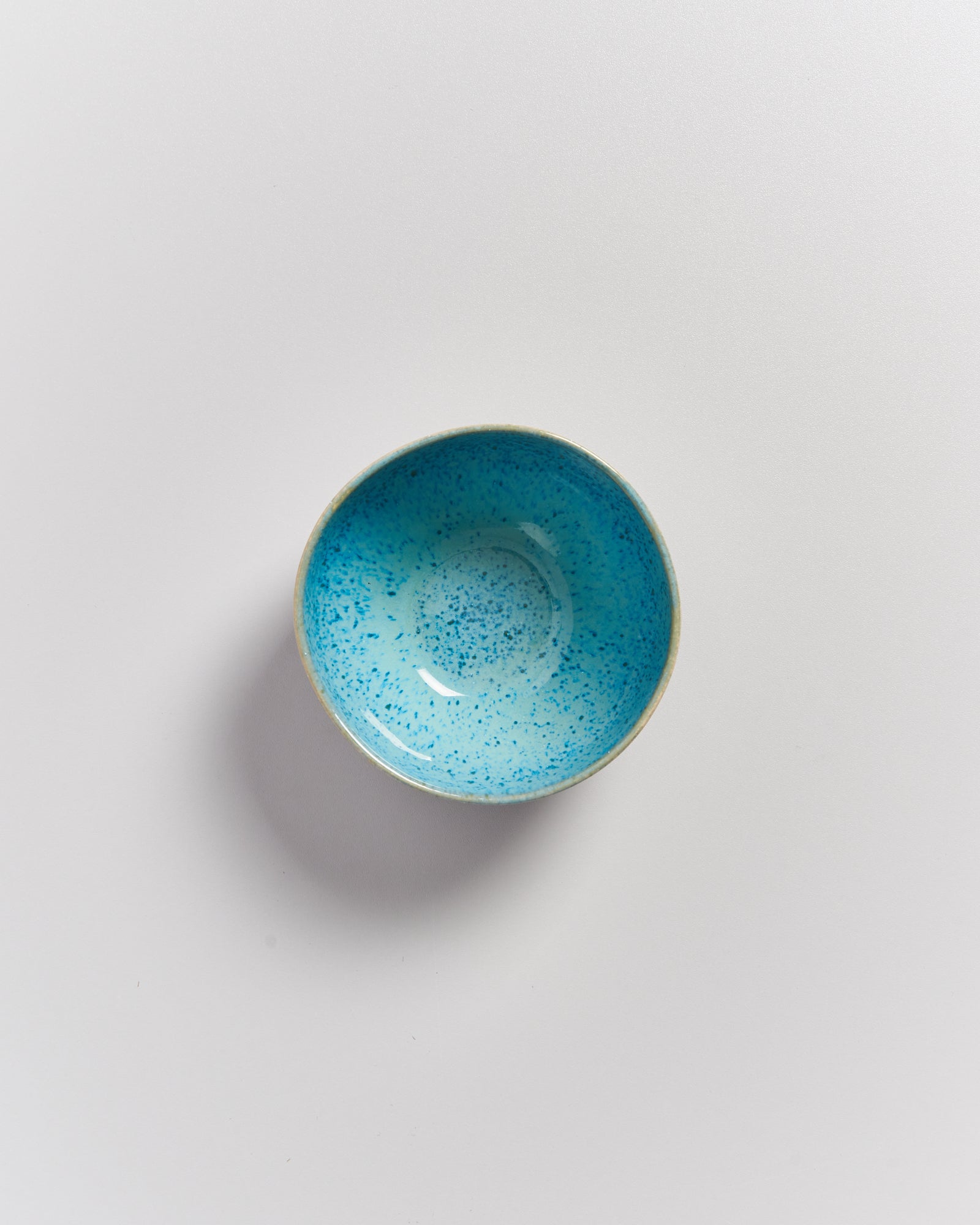 Kleine, hellblaue, gesprenkelte Schale auf weißem Hintergrund.