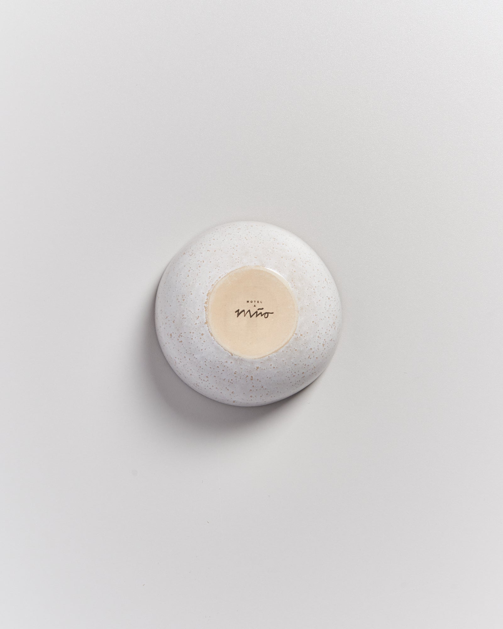 Rückseite einer kleinen weißen Schale auf hellem Hintergrund mit dem Text "Hotel Miro".