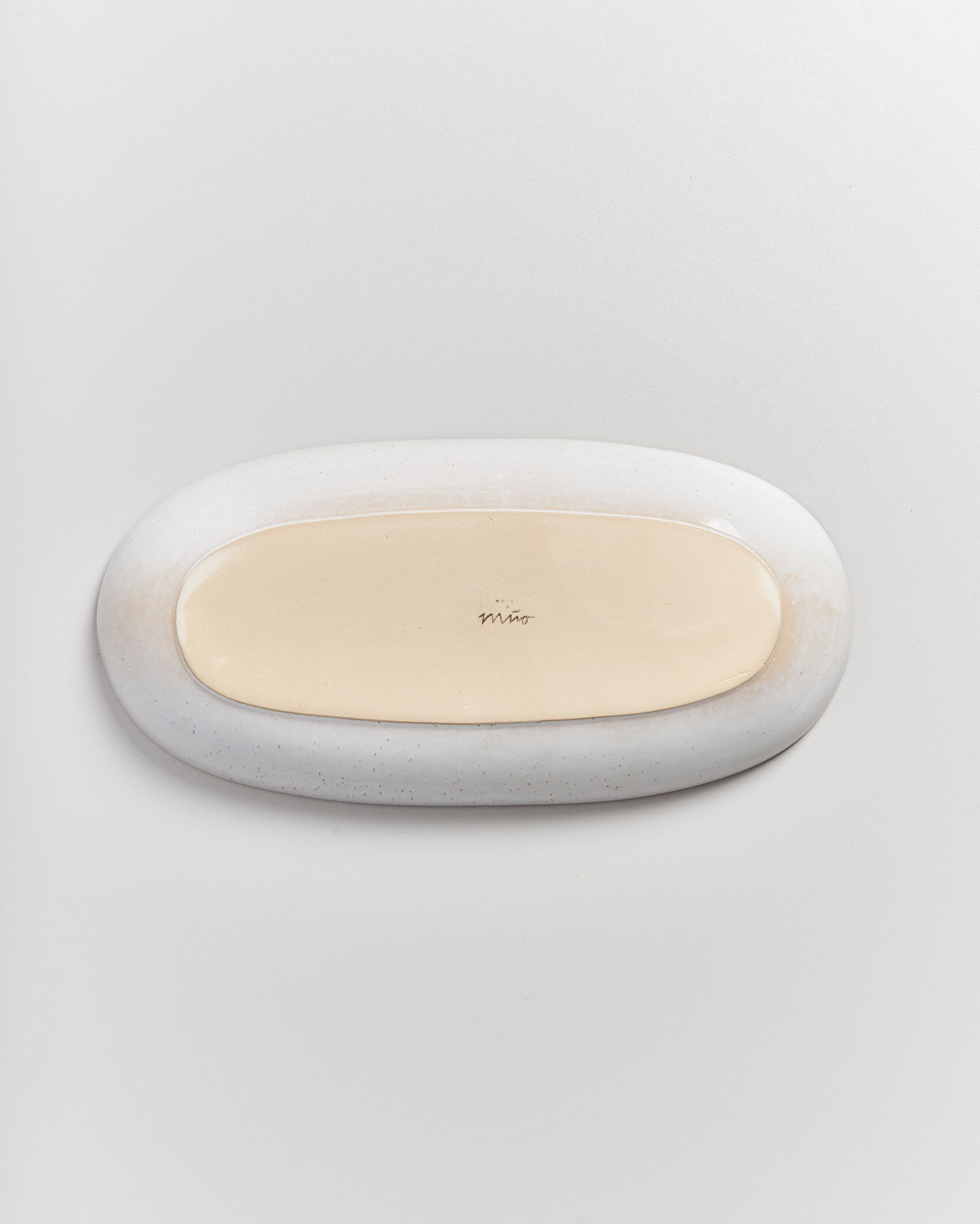 Ovaler, zweifarbiger Keramikteller mit hellem Zentrum und dunklerem Rand auf weißem Hintergrund.