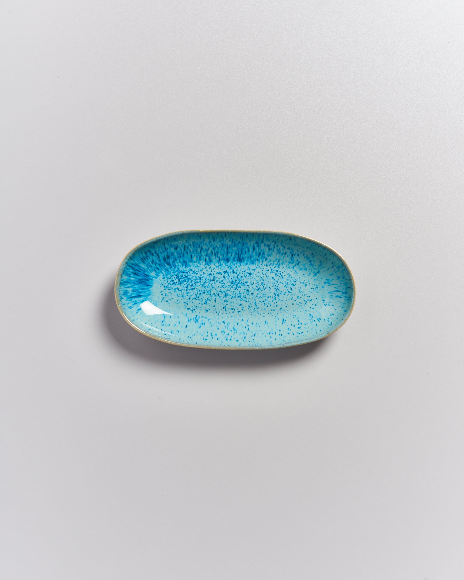 Ovaler Teller mit blauem Muster auf grauem Hintergrund.