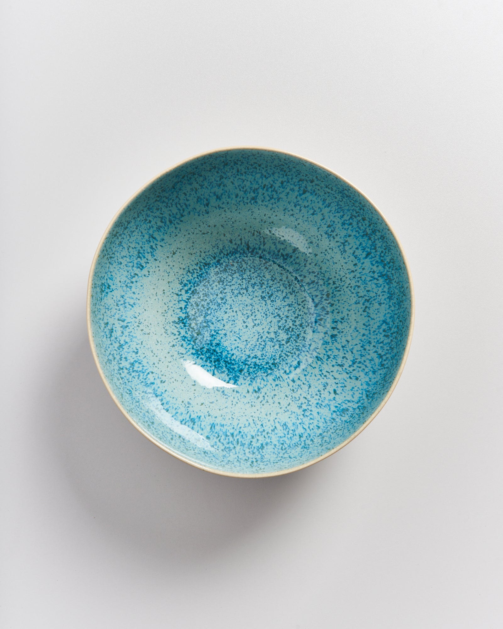 Hellblaue Schale mit gesprenkeltem Muster auf weißem Hintergrund fotografiert.