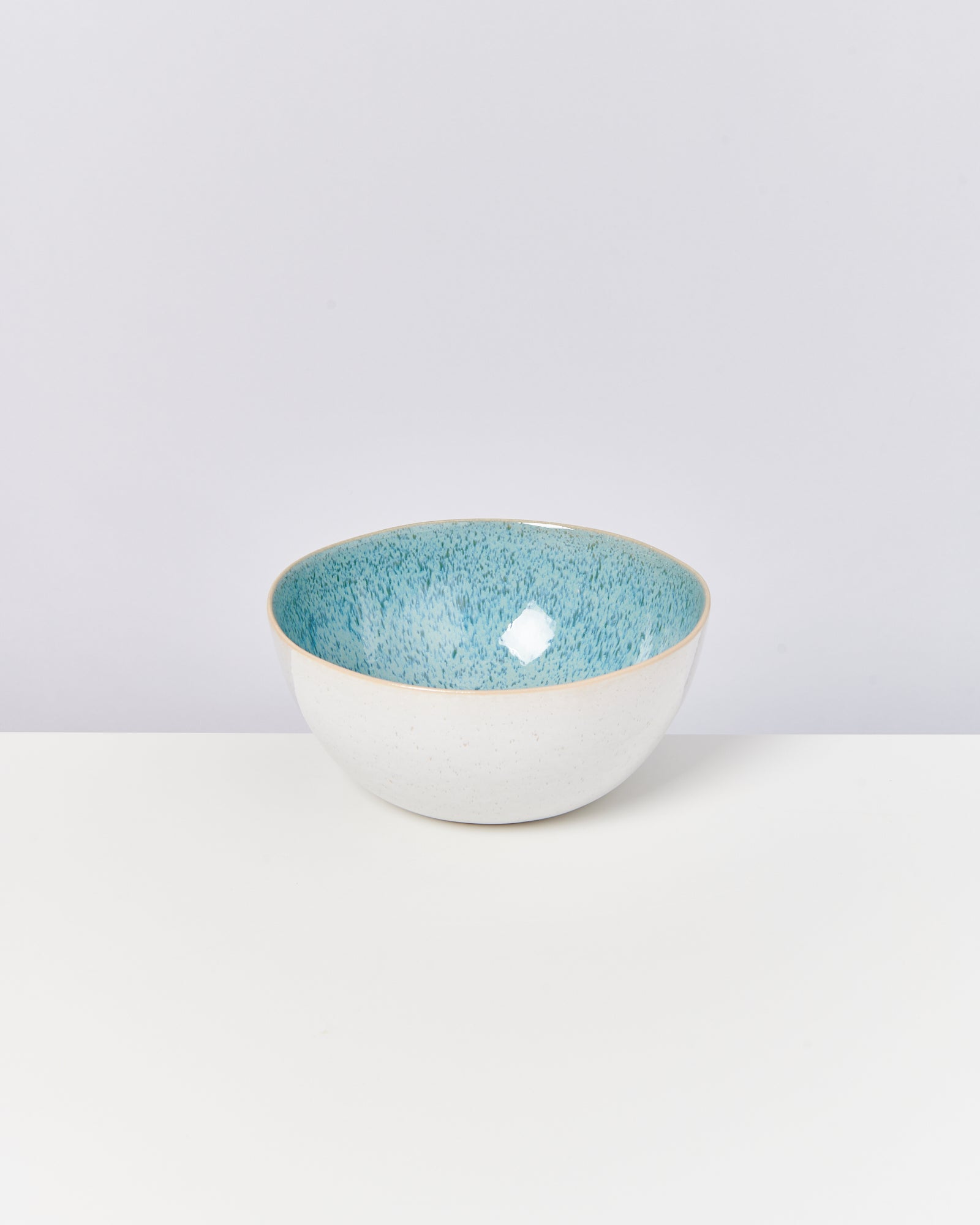 Weiße Schale mit blauem Innenrand auf weißem Hintergrund.