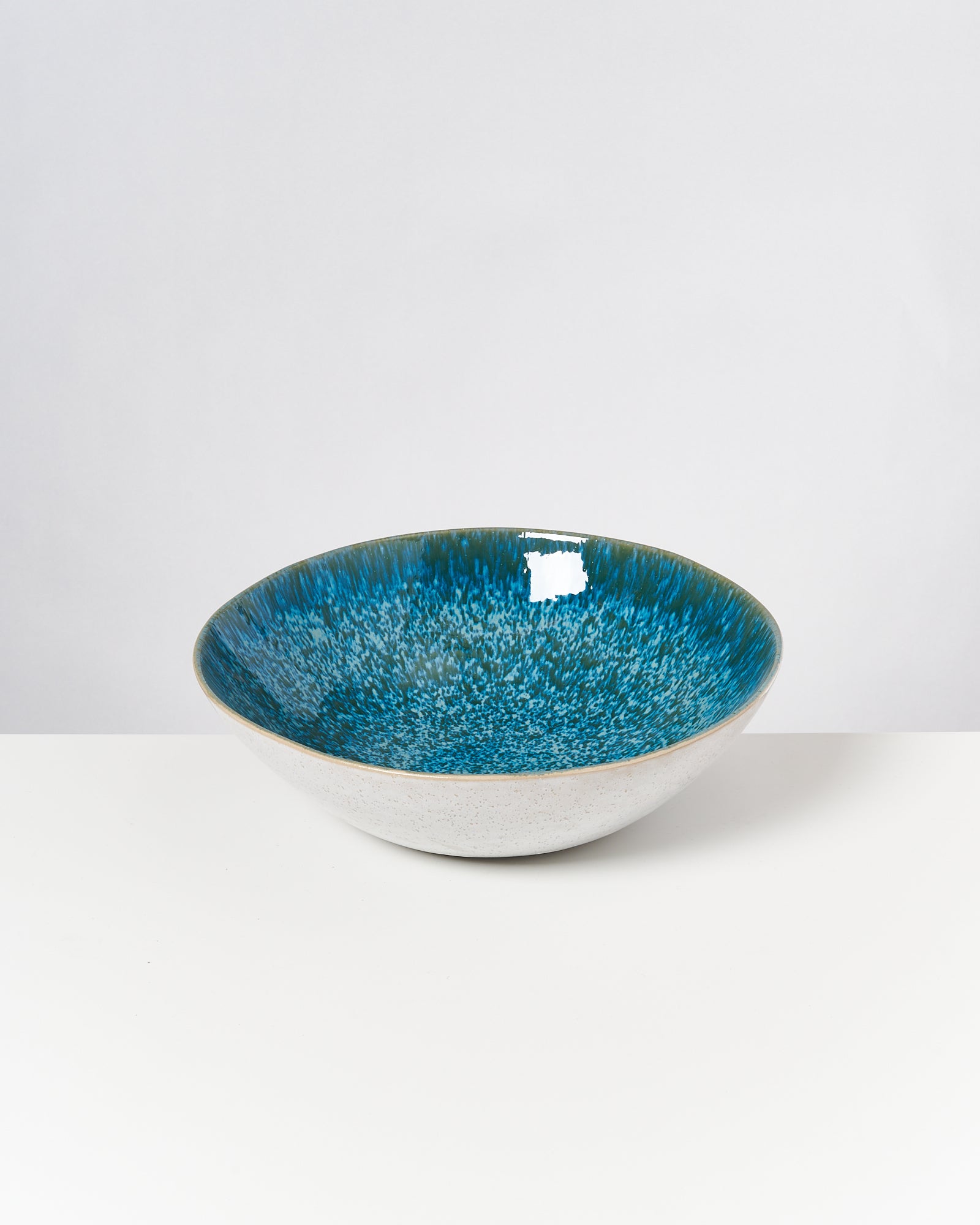 Eine Schüssel mit blau-grünem Innenbereich auf weißem Hintergrund.