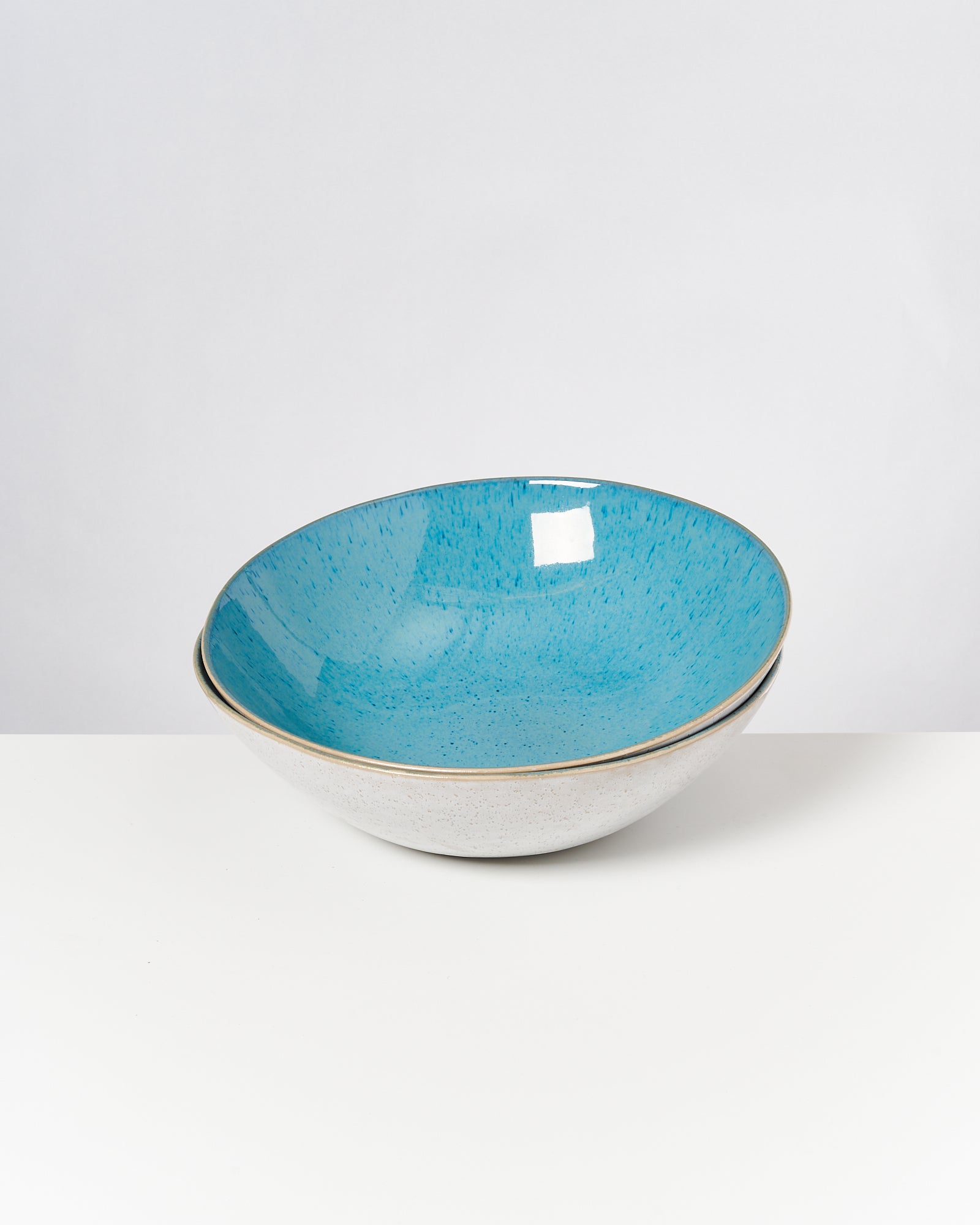 Keramikschale mit blauer Innenseite und weißer Außenseite auf weißem Hintergrund.