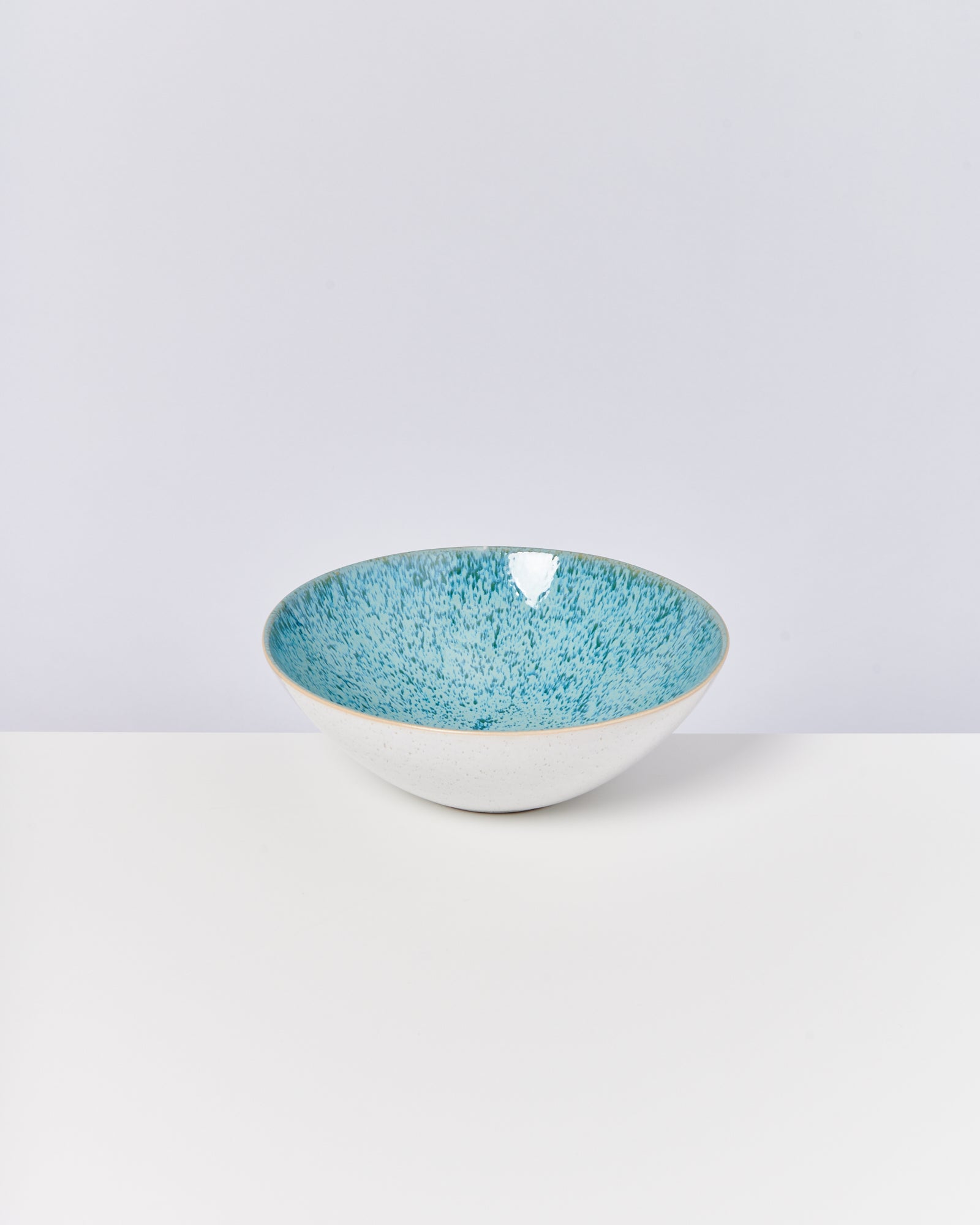 Weiße Schale mit türkis gesprenkelter Innenseite auf weißem Hintergrund.