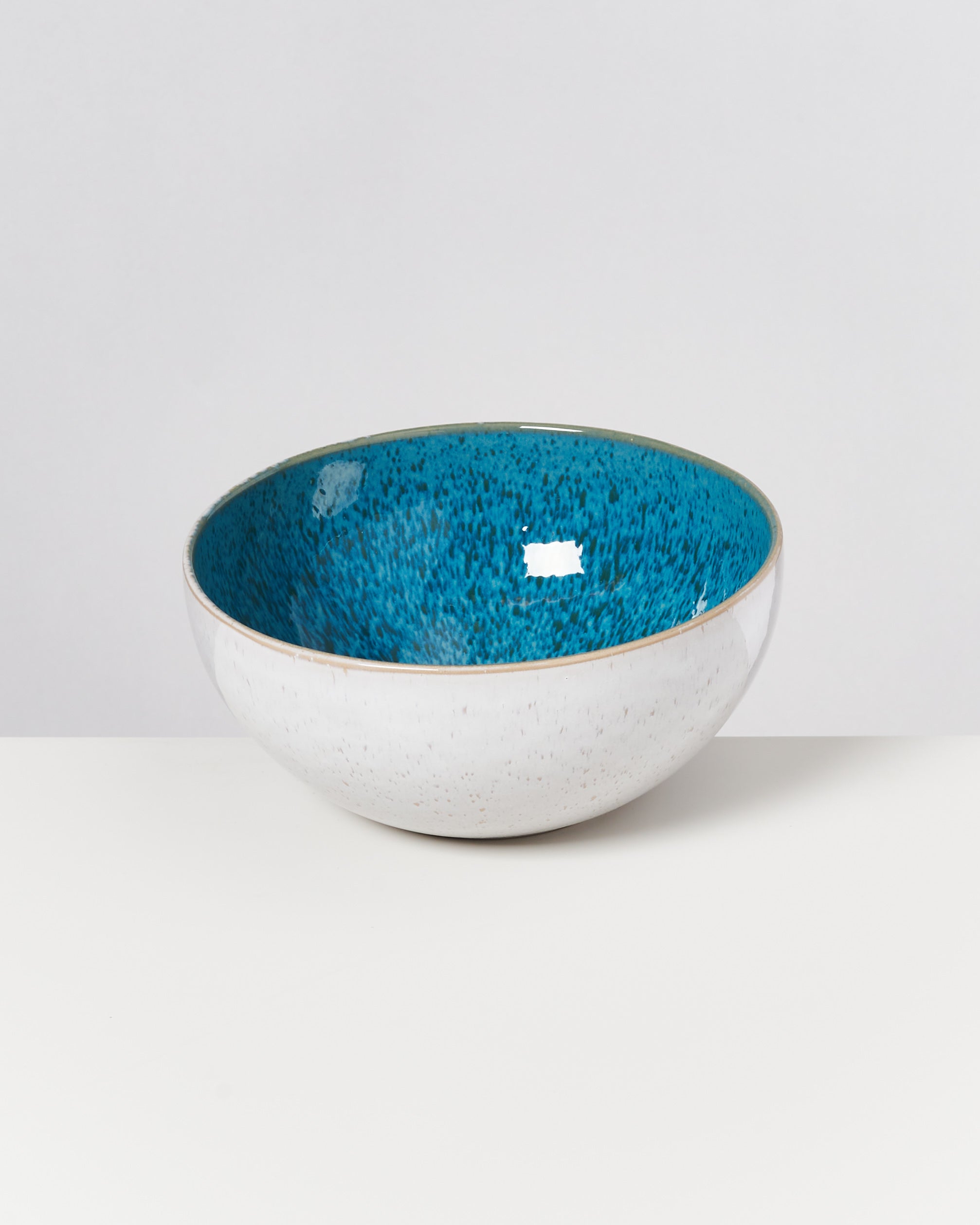 Weiße Schale mit blauem, gesprenkeltem Innenbereich auf einem weißen Hintergrund.