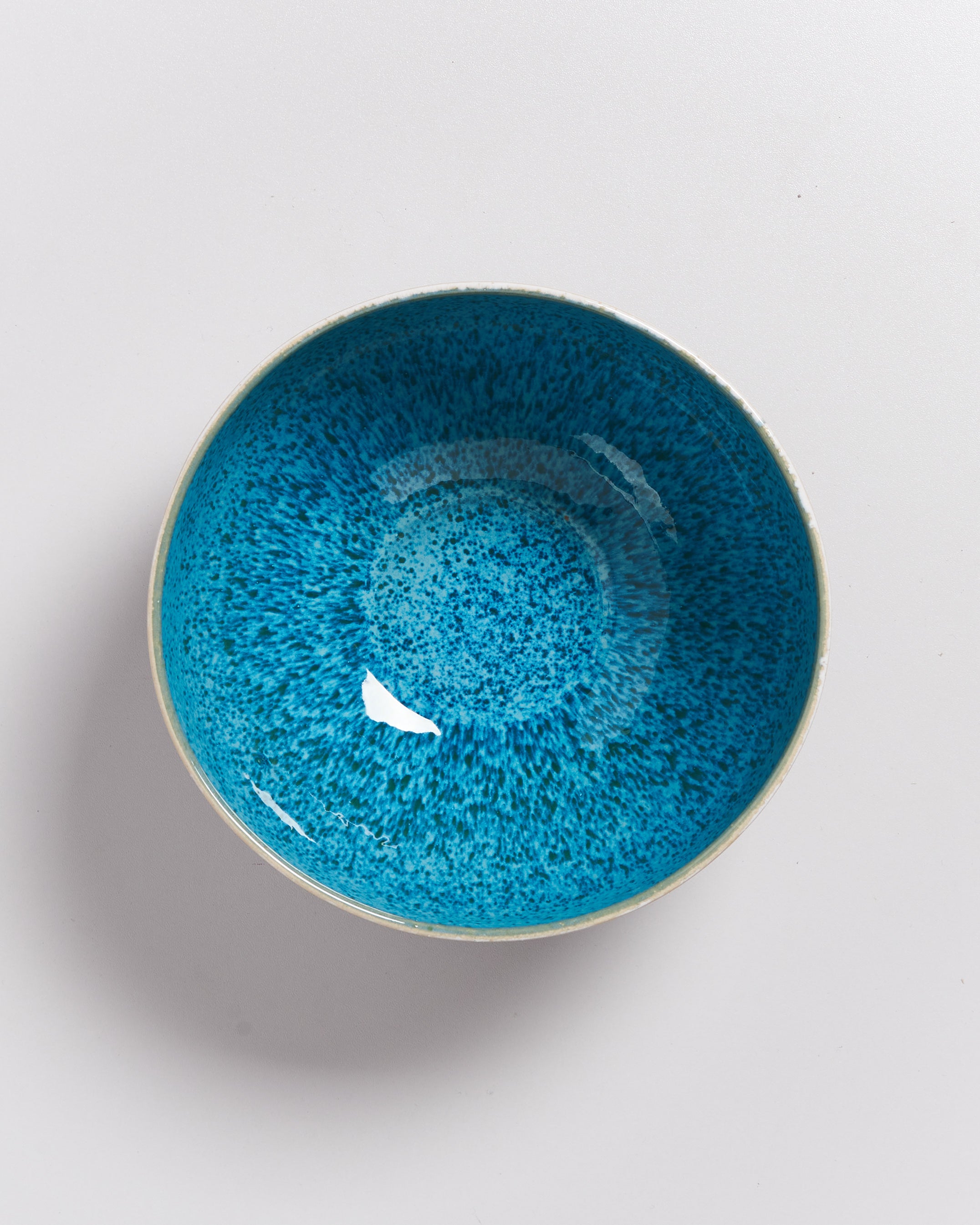 Blaue Keramikschale mit gesprenkeltem Muster auf weißem Hintergrund.
