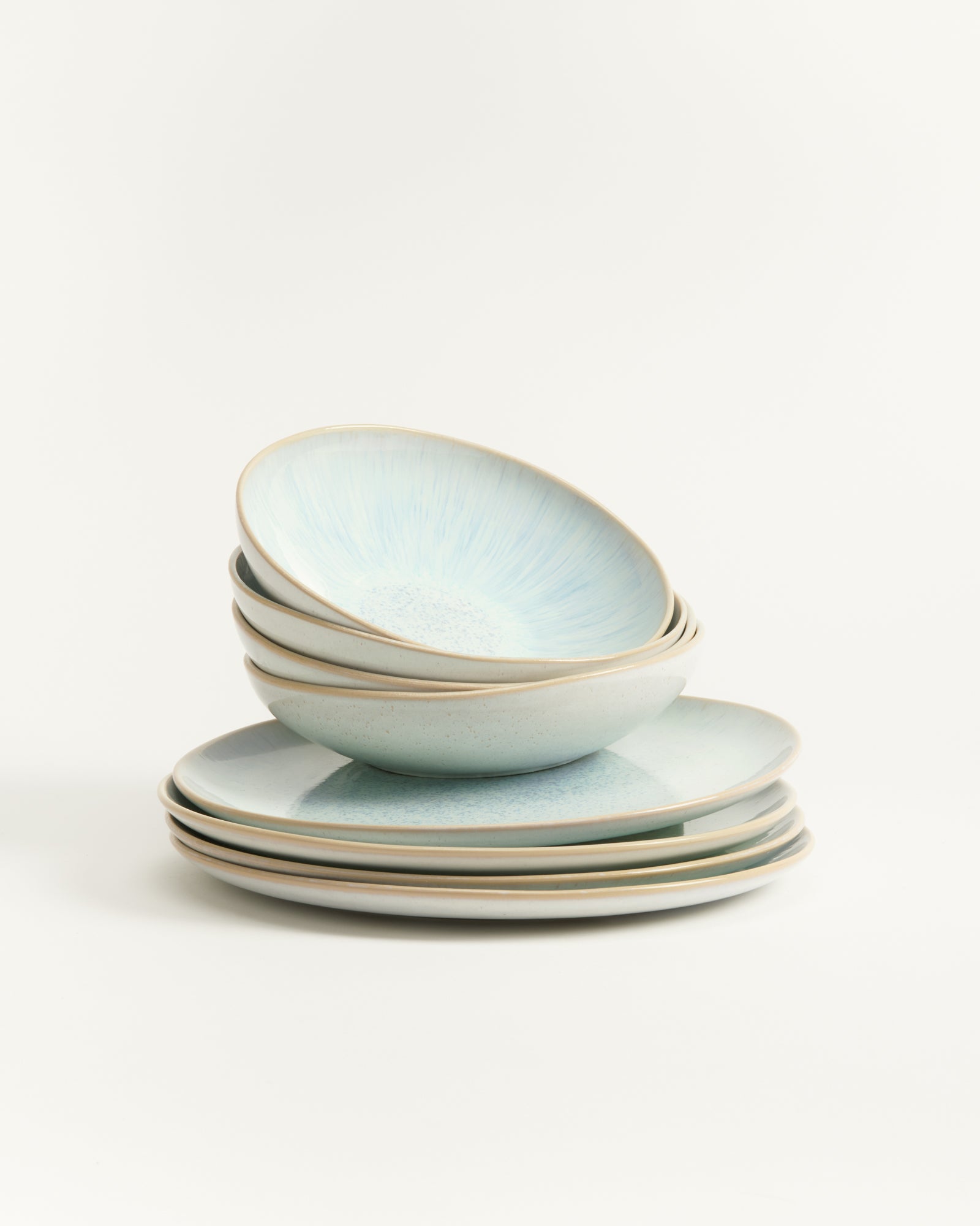 Ein Stapel hellblaue, keramische Schalen und Teller auf weißem Hintergrund.
