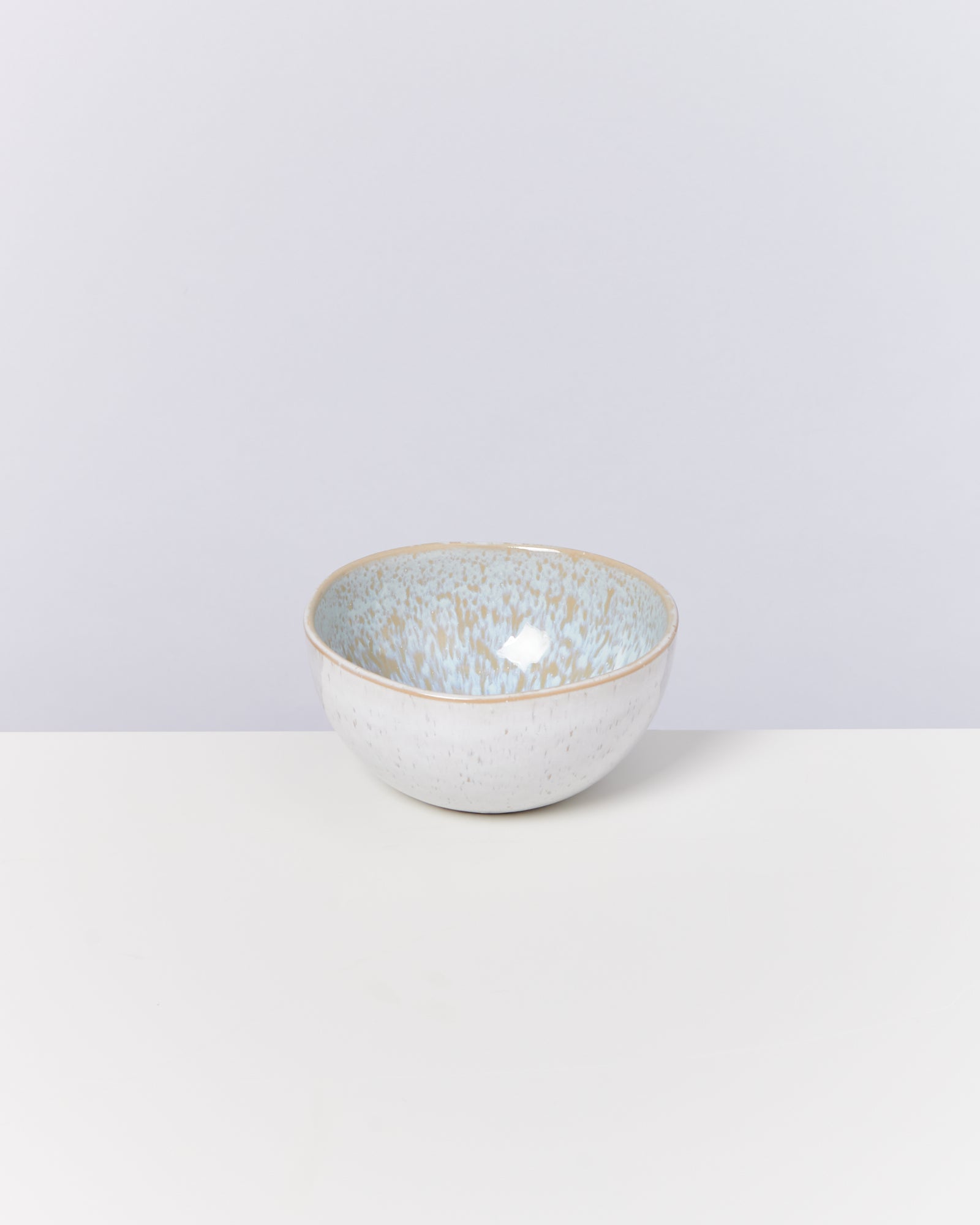 Keramikschüssel mit blauer und hellbrauner Glasur auf weißem Hintergrund.