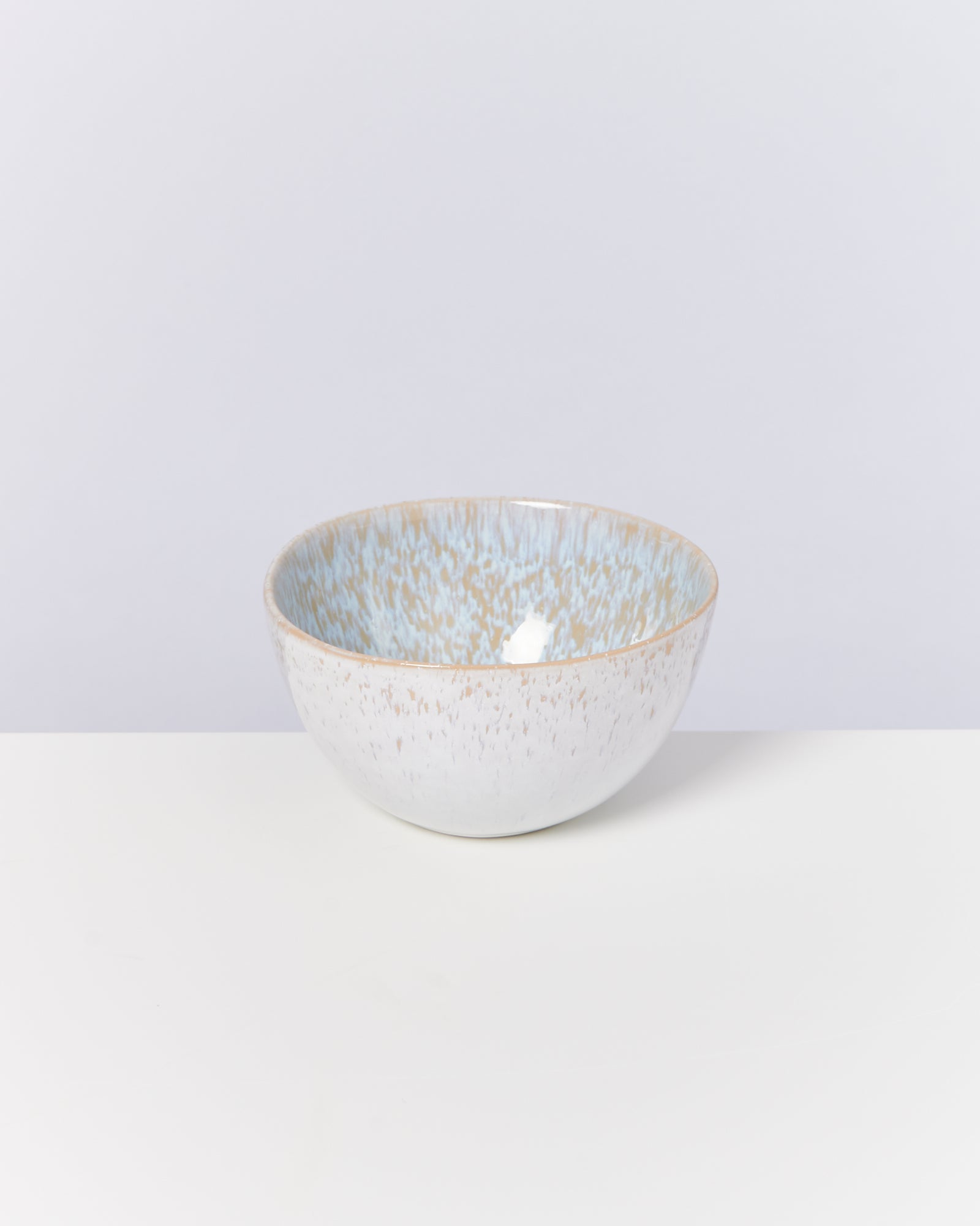 Keramikschale mit blauer und beiger Musterung steht auf einem weißen Hintergrund.