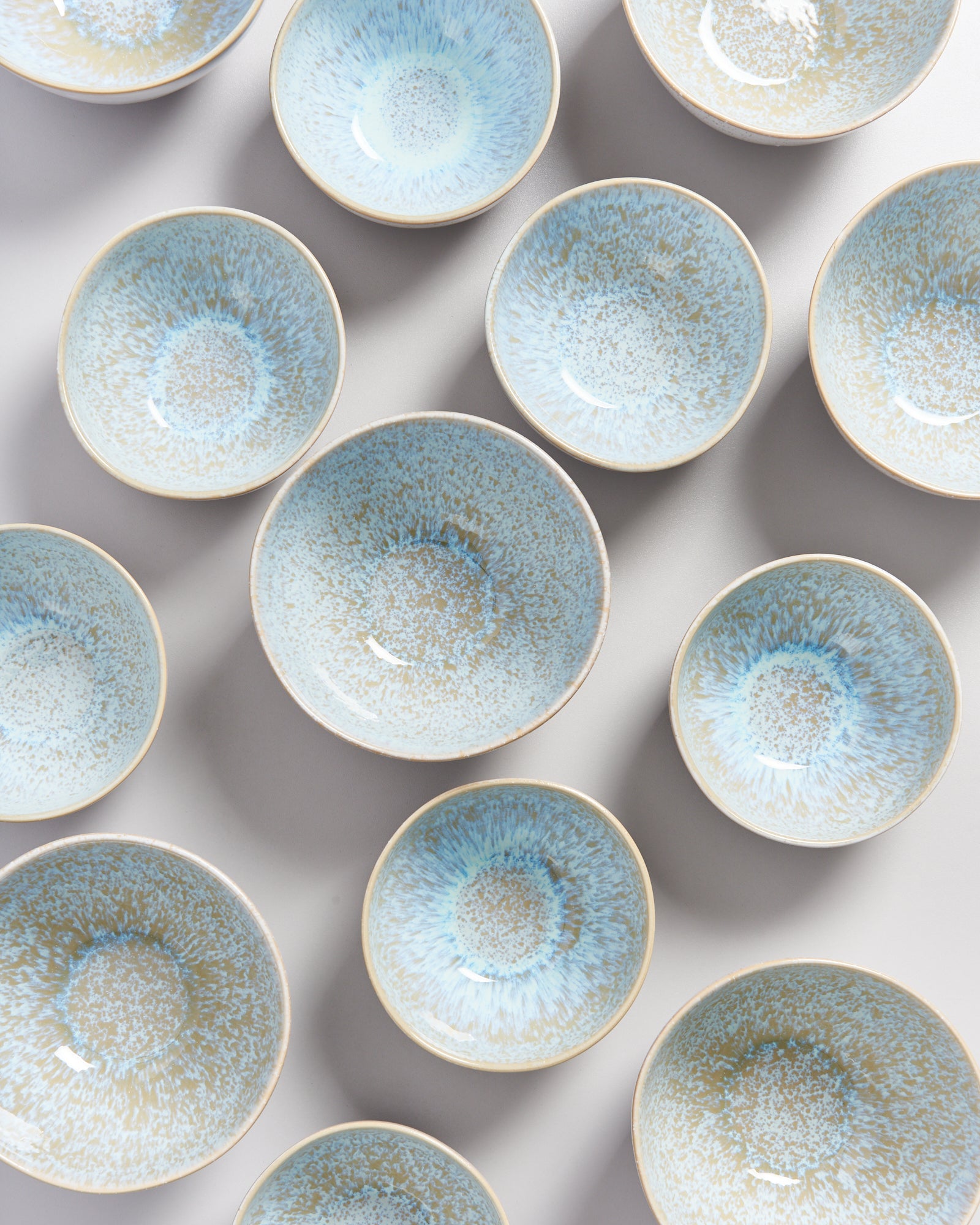 Mehrere kleine, blaue Keramikschalen mit heller Innenglasur auf einem grauen Hintergrund.