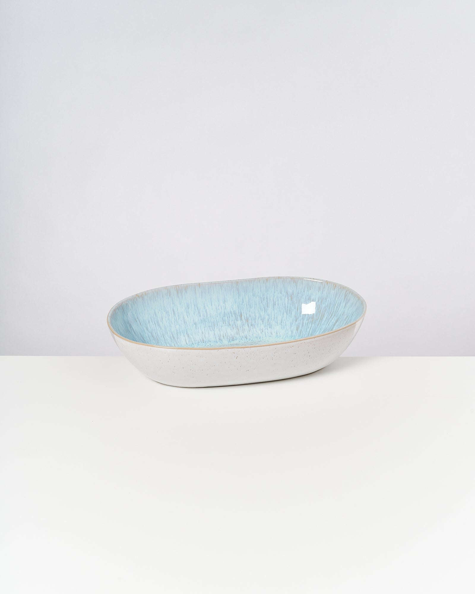Ovale Schale mit hellblauer Innenseite und heller Außenseite auf weißem Hintergrund.