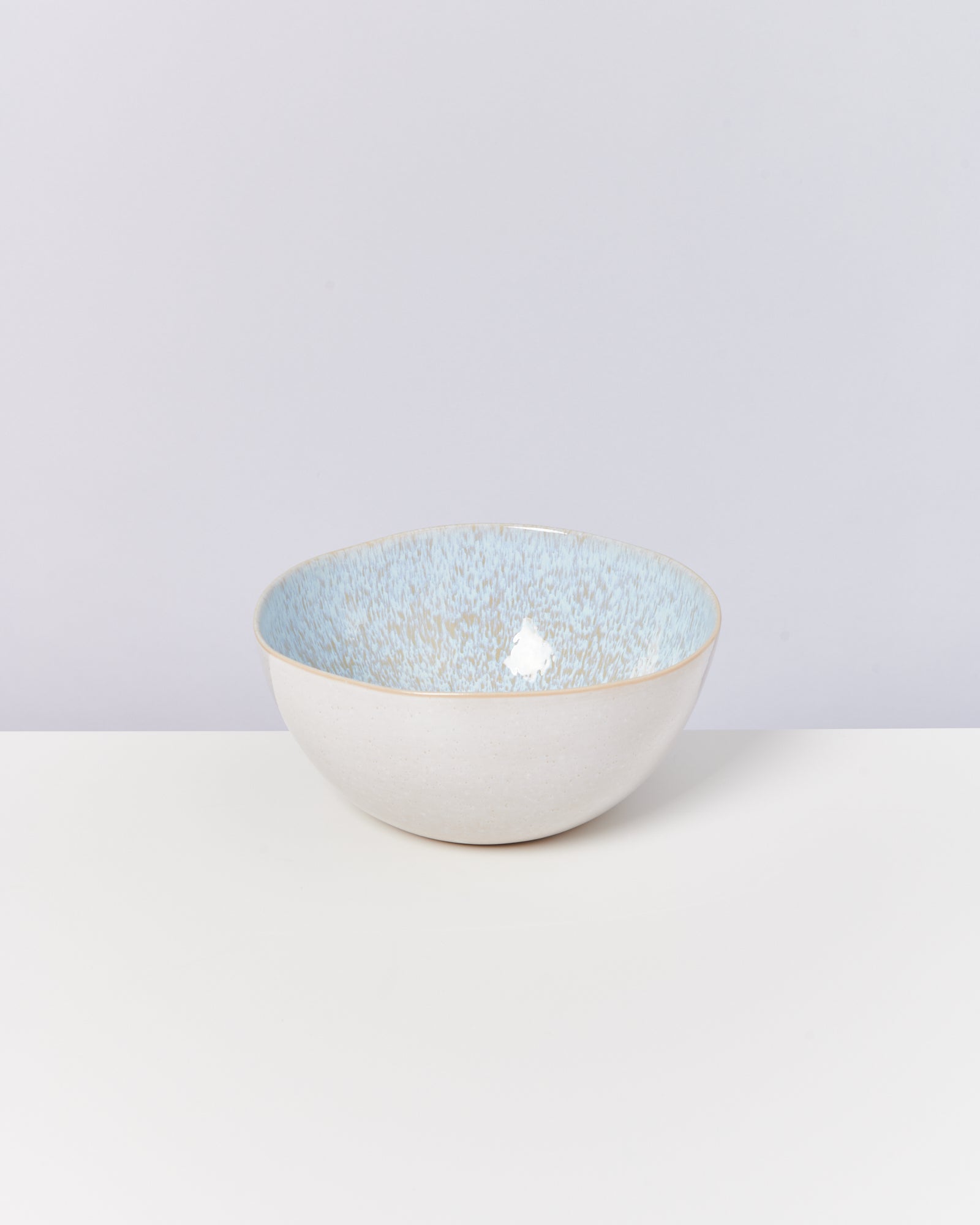 Keramikschale mit weiß-blauer Innenseite auf hellem Hintergrund.