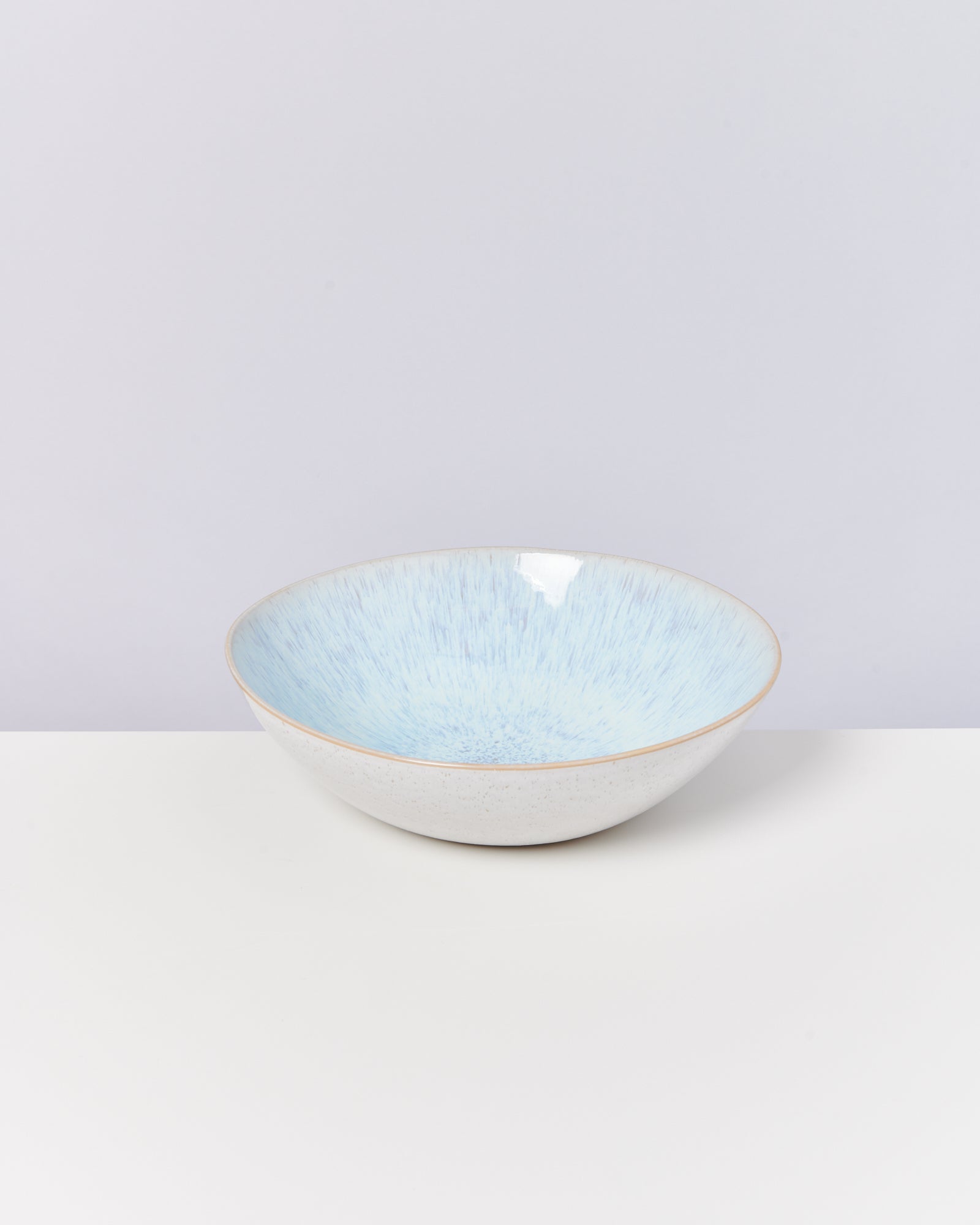 Blau-weiße Keramikschale auf weißem Untergrund vor einer hellen Wand.