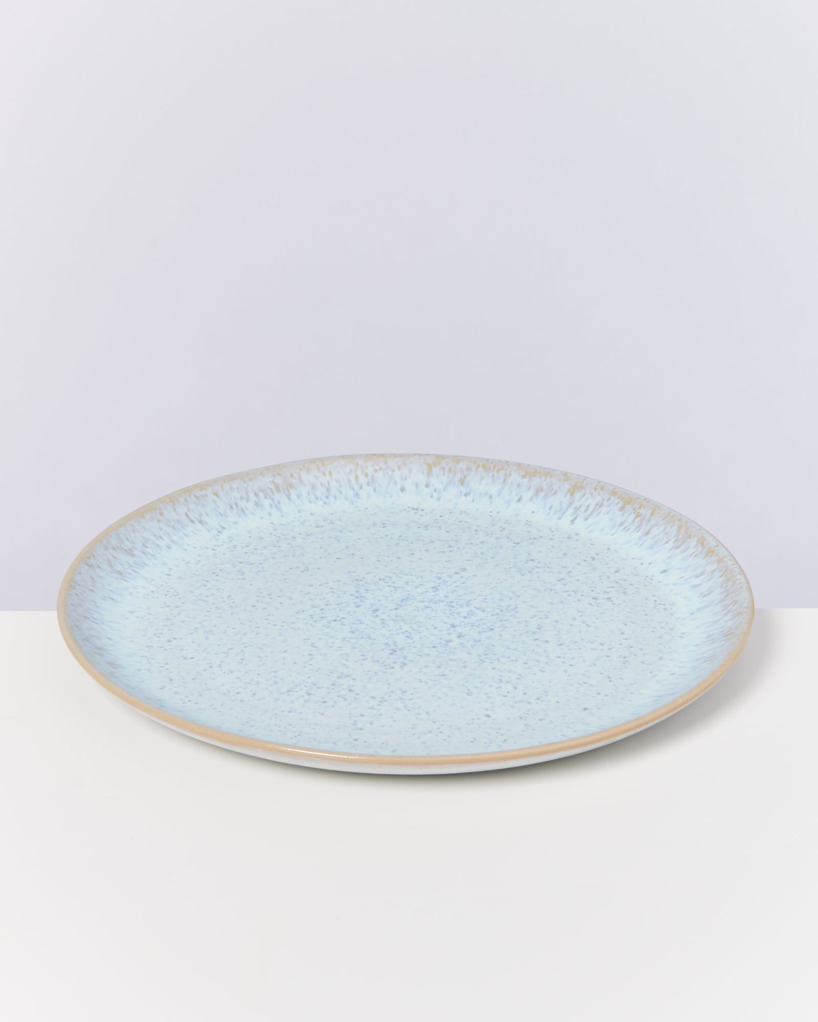 Hellblaue, flache Keramikplatte mit gesprenkelter Oberfläche auf weißem Hintergrund.