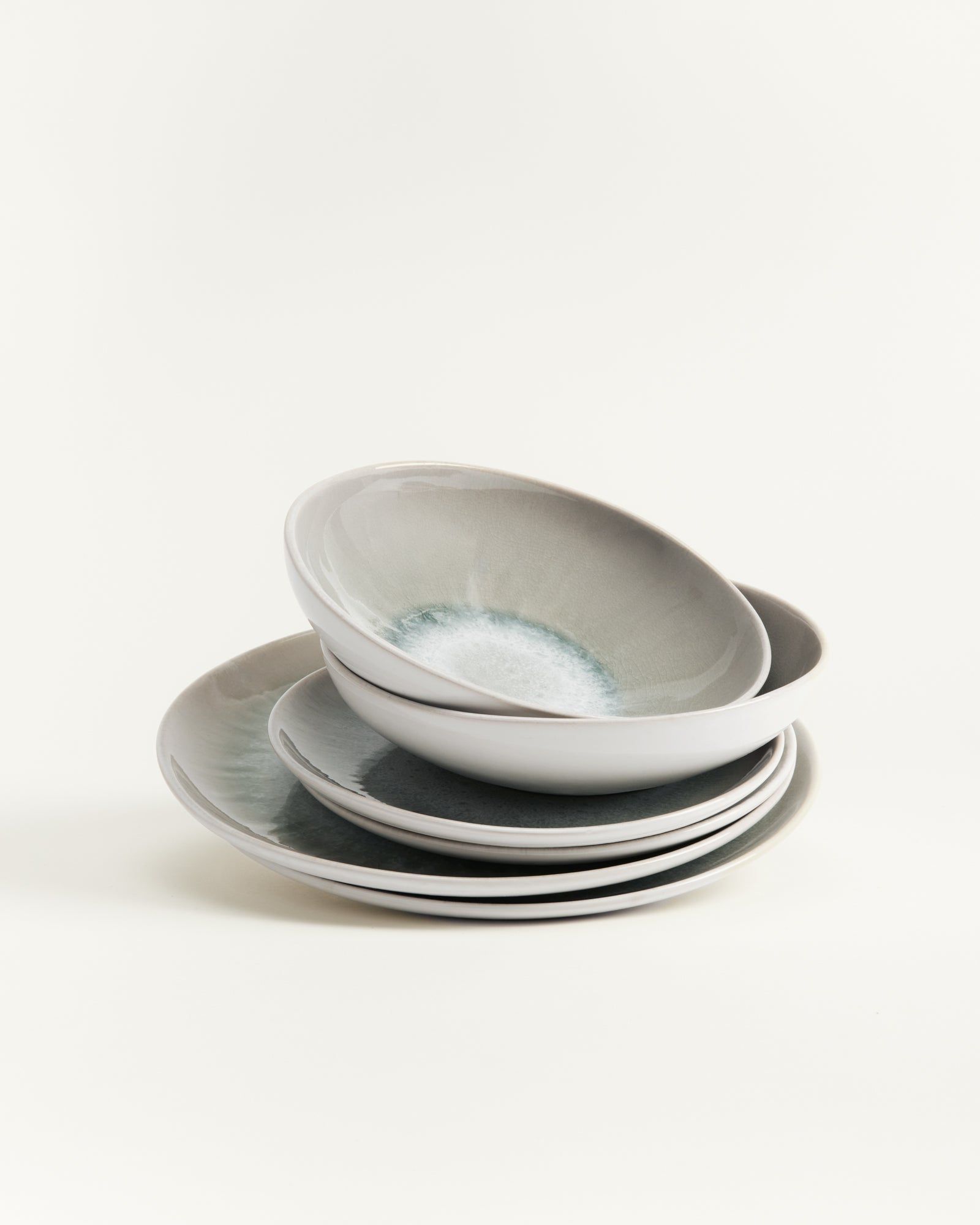 Ein Stapel von vier grauen Keramiktellern auf einem weißen Hintergrund.
