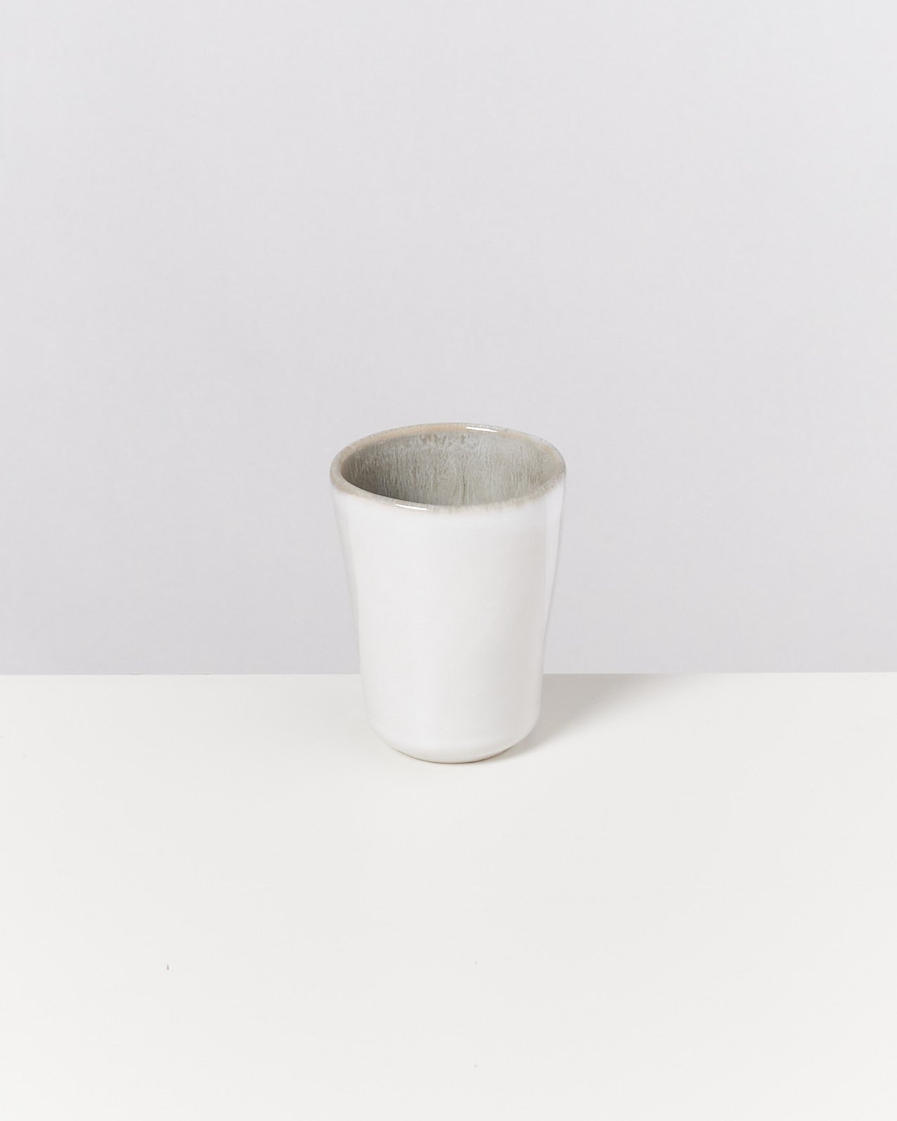 Weiße Keramiktasse auf einem weißen Hintergrund.