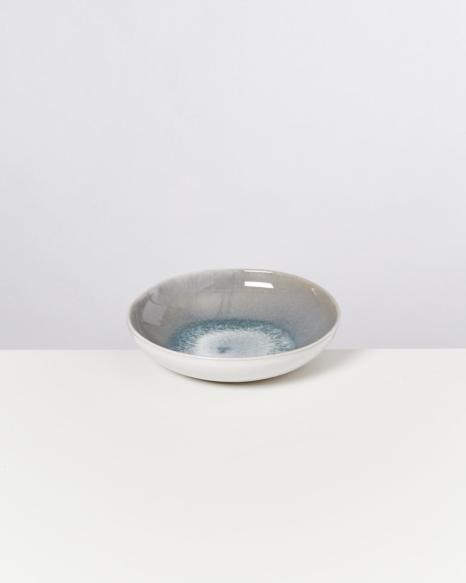 Graue und blaue Keramikschale auf weißem Hintergrund.