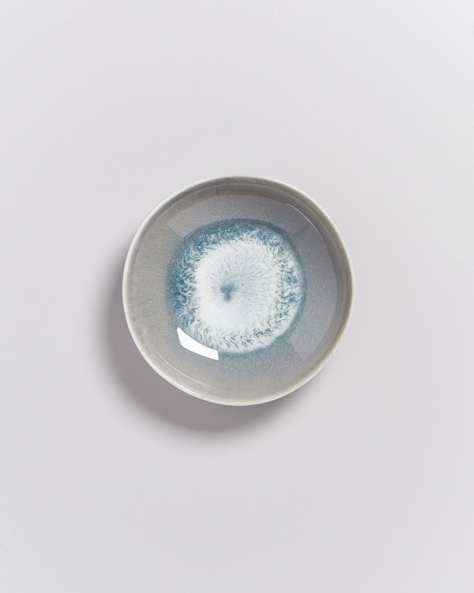 Keramikschale mit einem blauen, wirbelähnlichen Muster auf hellem Hintergrund.