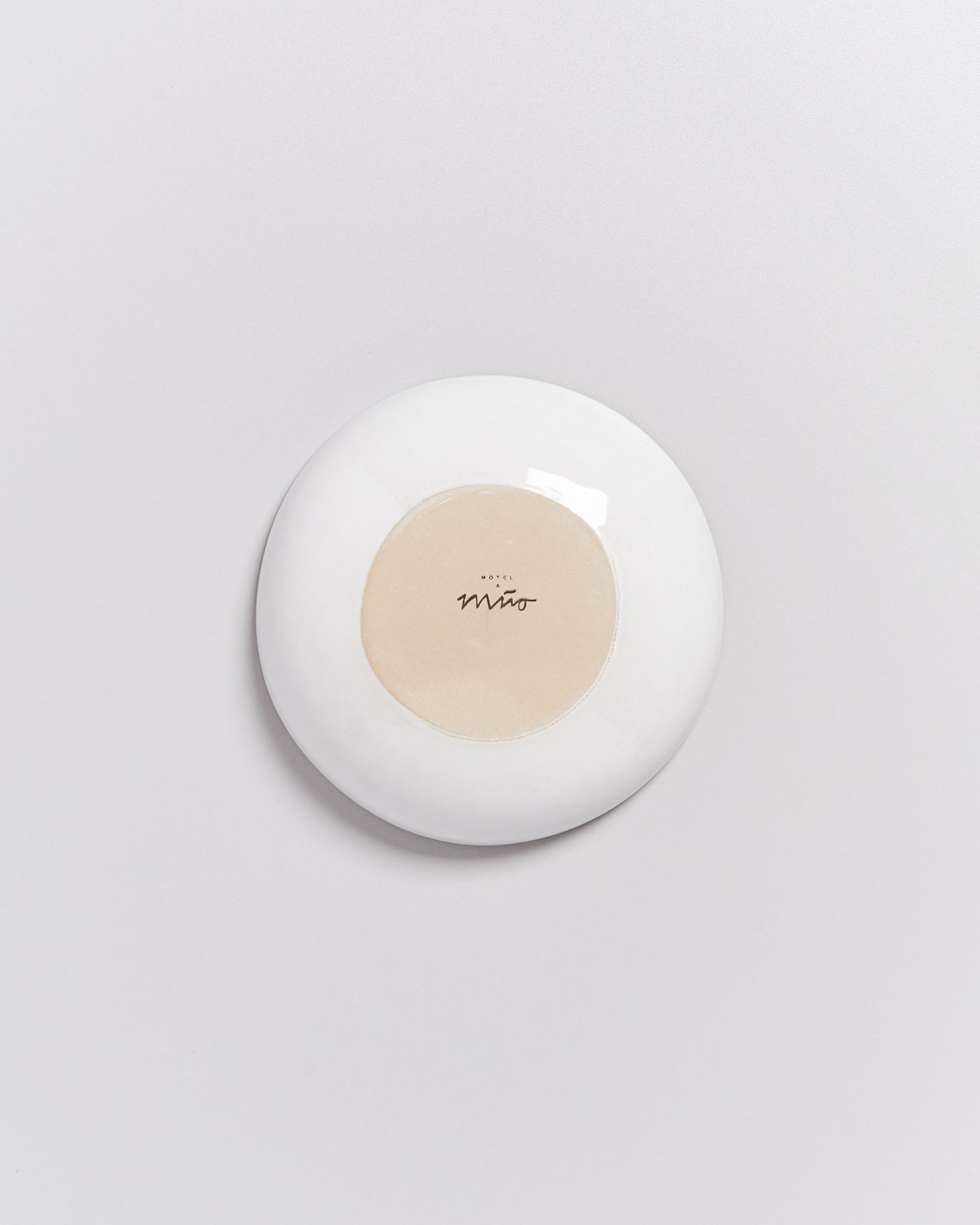 Weiße runde Seifenschale mit einem beigen Kreis in der Mitte, auf dem "Miro" steht.
