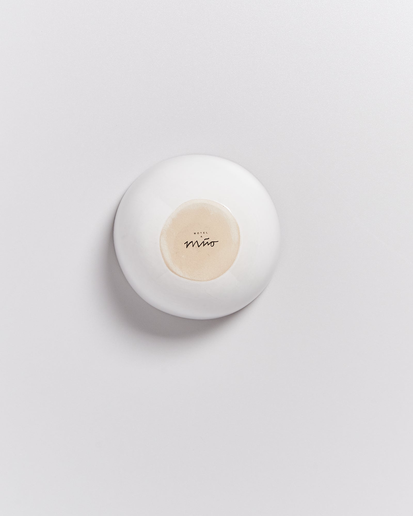 Eine weiße Schale mit einem Schriftzug im Inneren auf einem hellen Hintergrund.