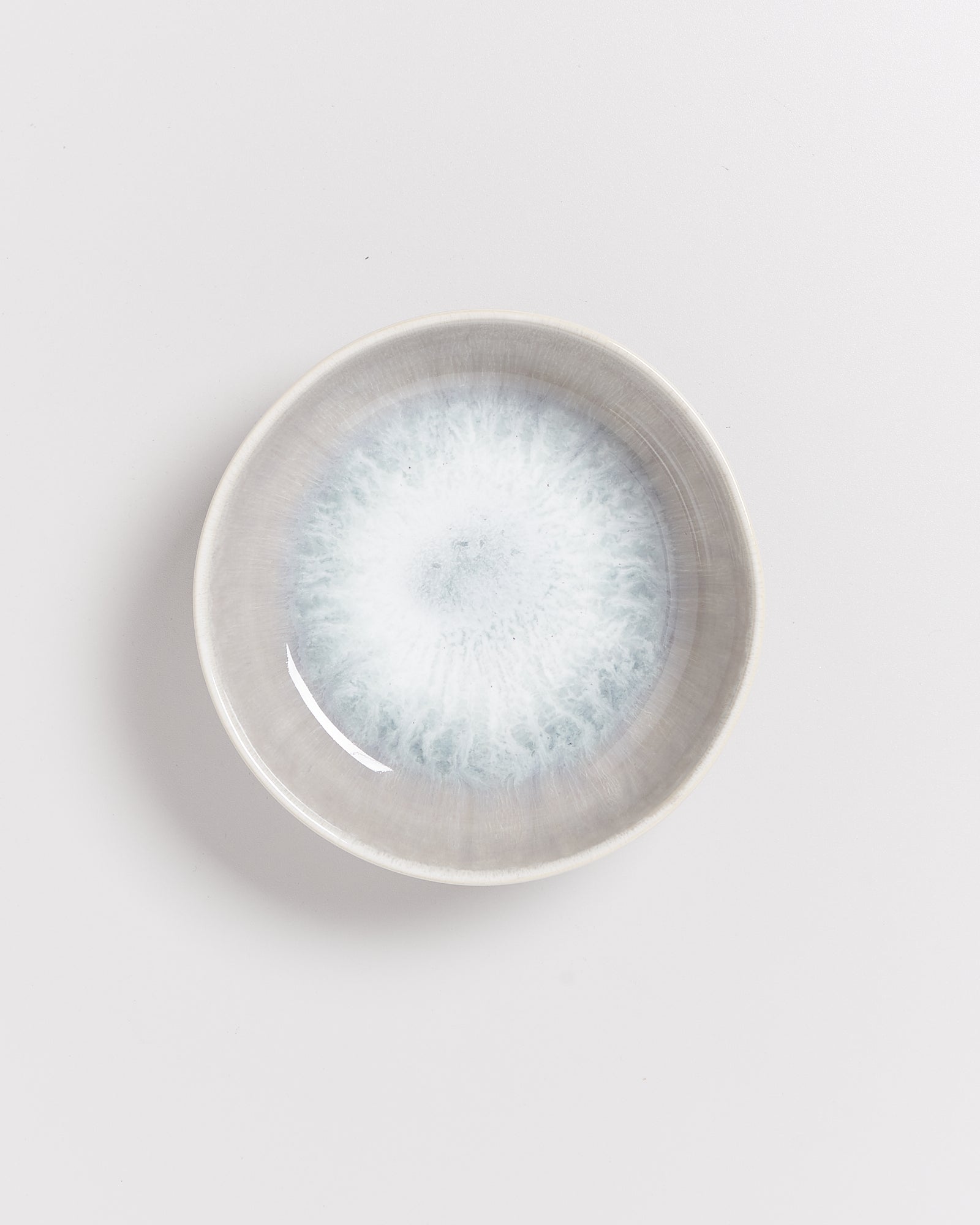 Keramikteller mit grauem und hellblauem Muster auf weißem Hintergrund.