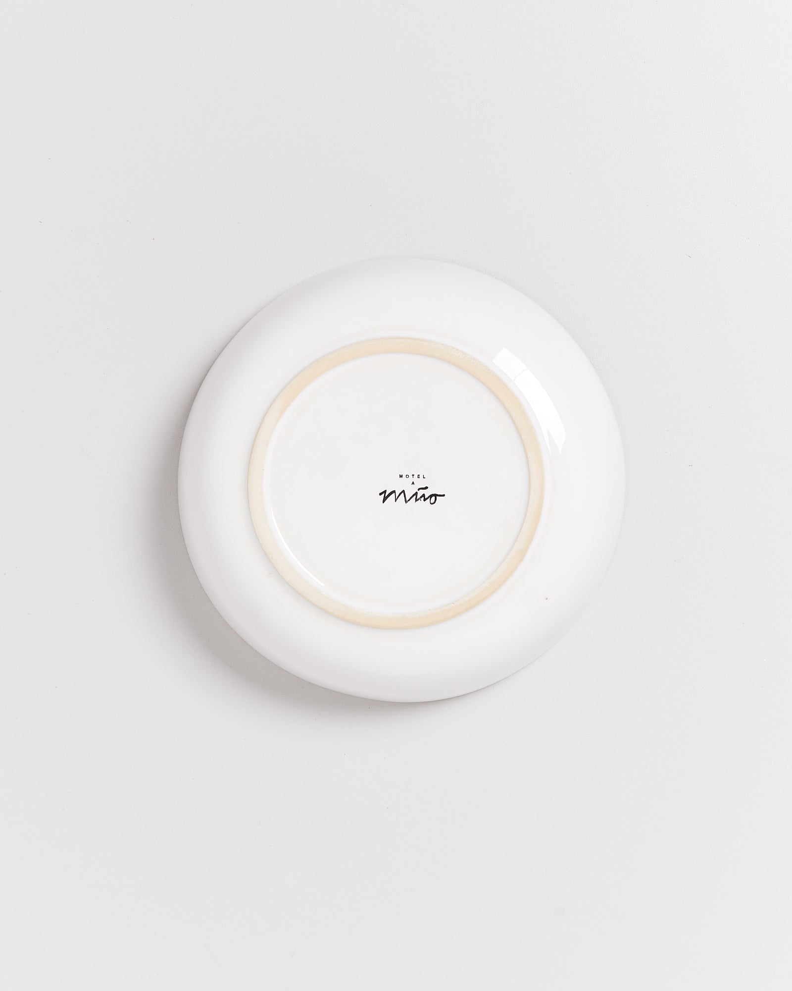 Weiße Keramikschale, auf der Unterseite mit der Aufschrift "Hotel Miró" in schwarzer Schrift.