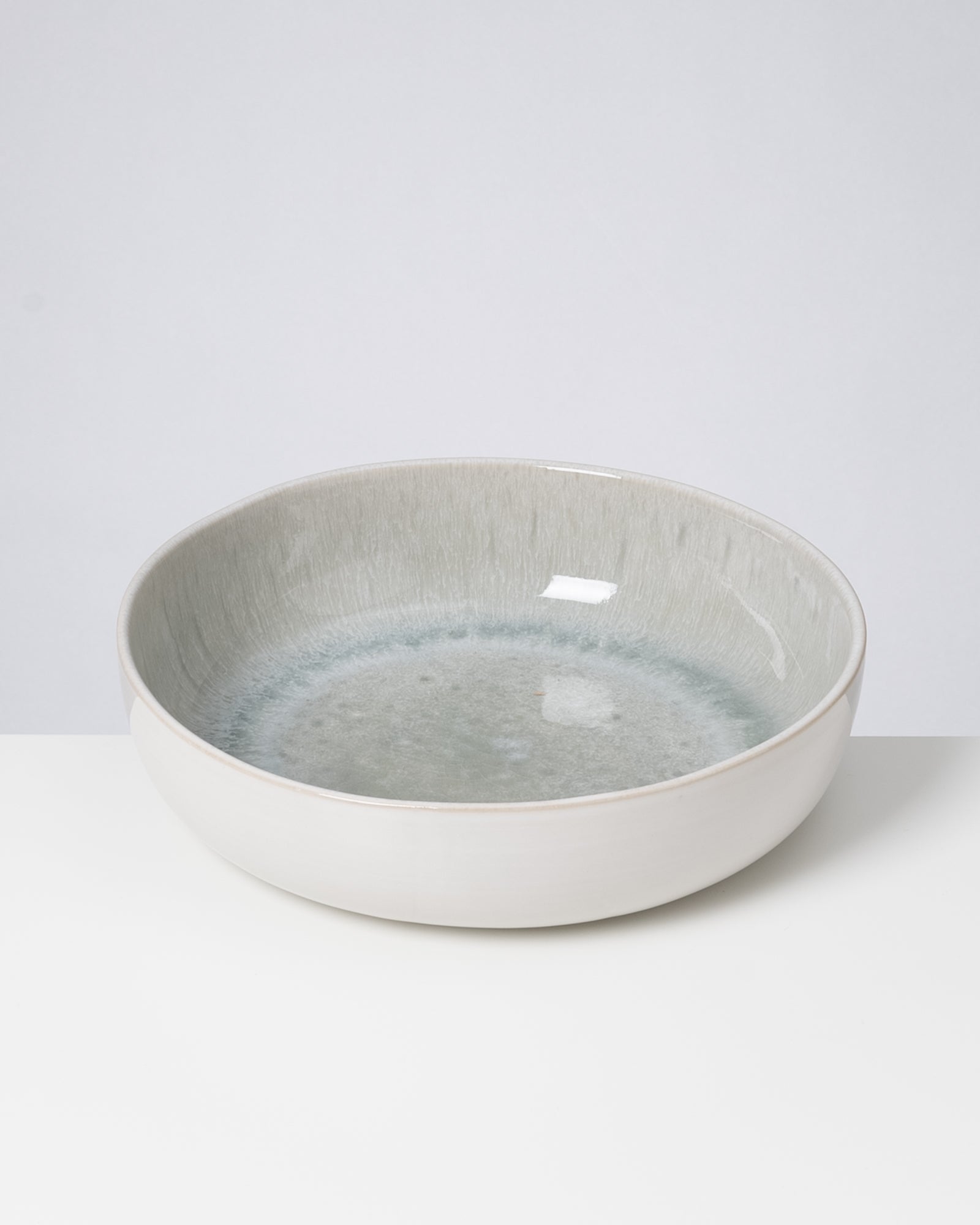 Graue, runde Keramikschale auf einem weißen Untergrund.