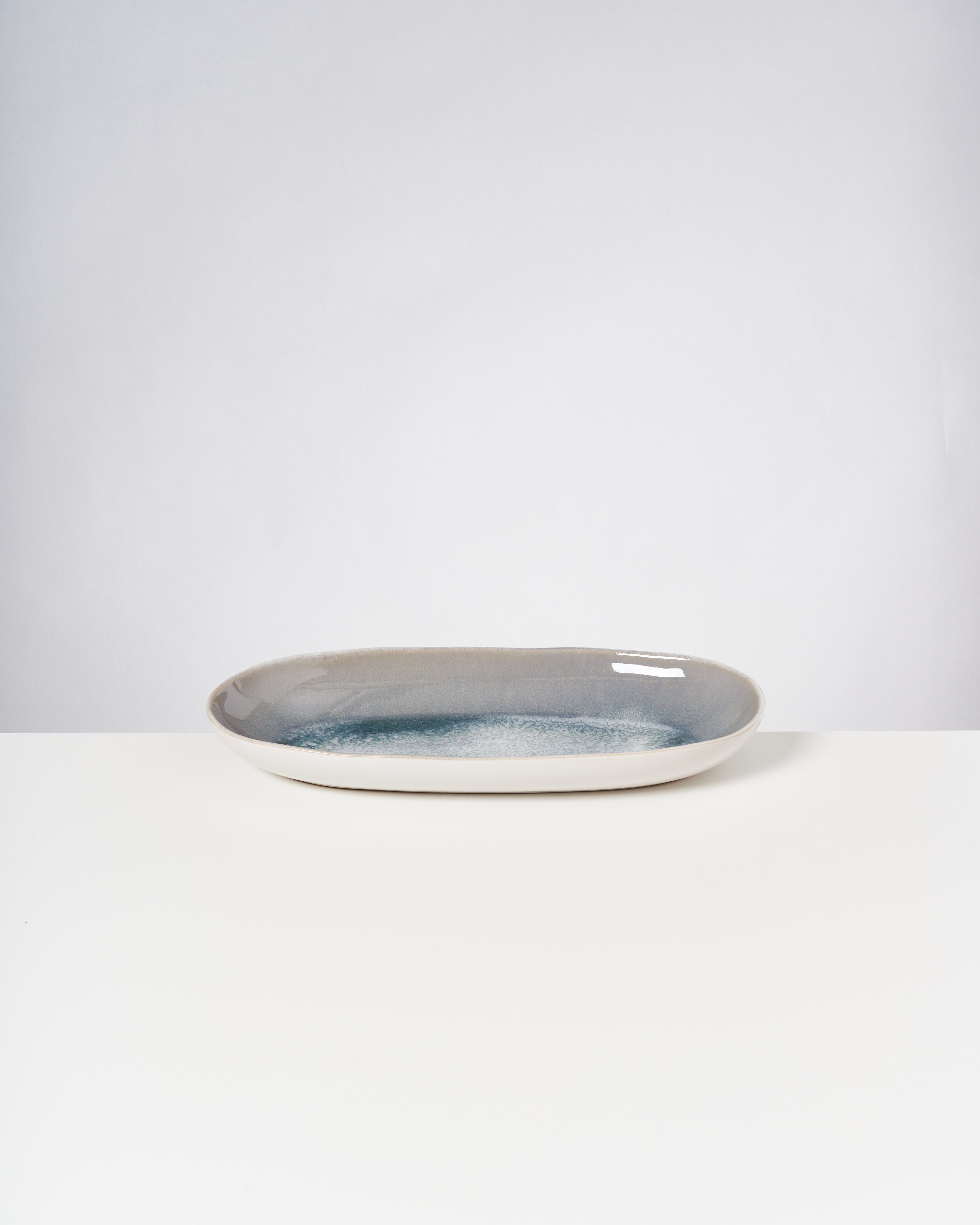 Langes, ovales Porzellantablett mit bläulicher Innenglasur auf einem weißen Hintergrund.