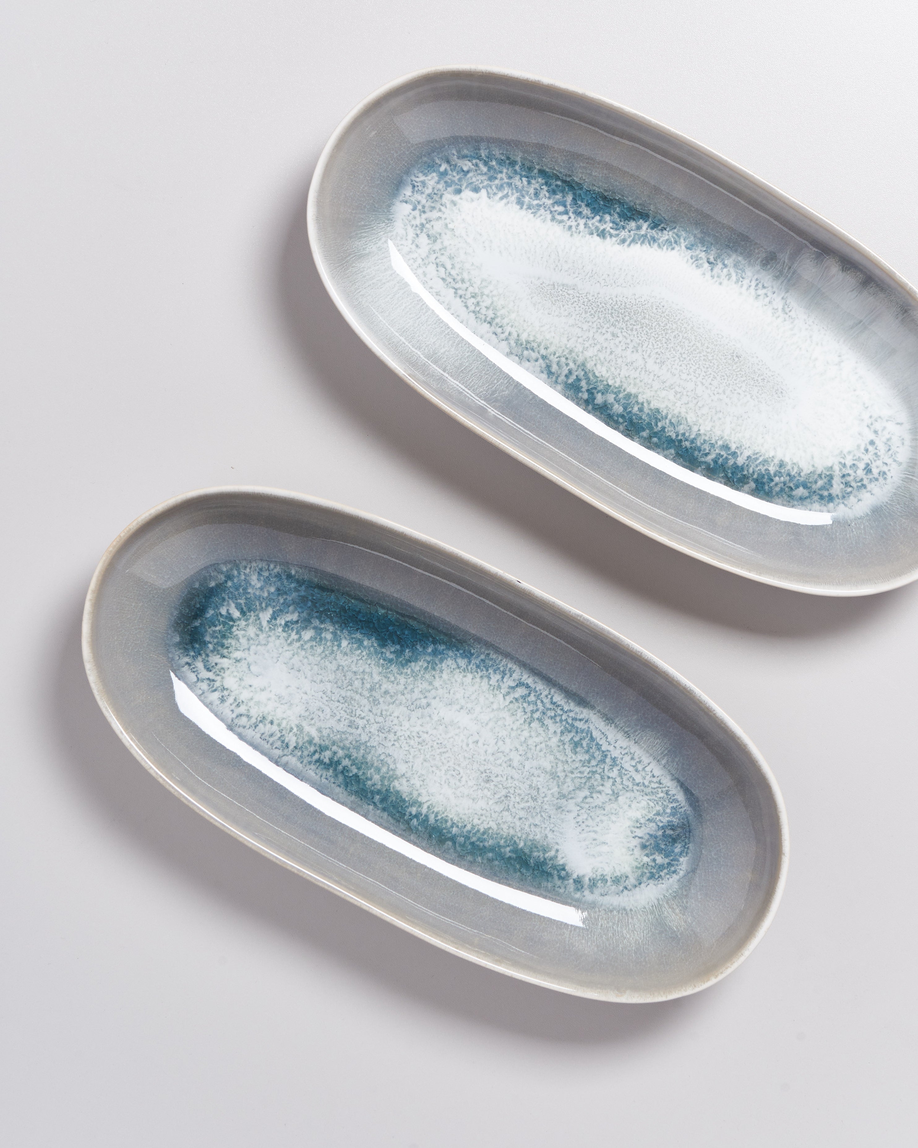 Zwei ovale Keramikteller mit blau-weißem Muster auf weißem Hintergrund.