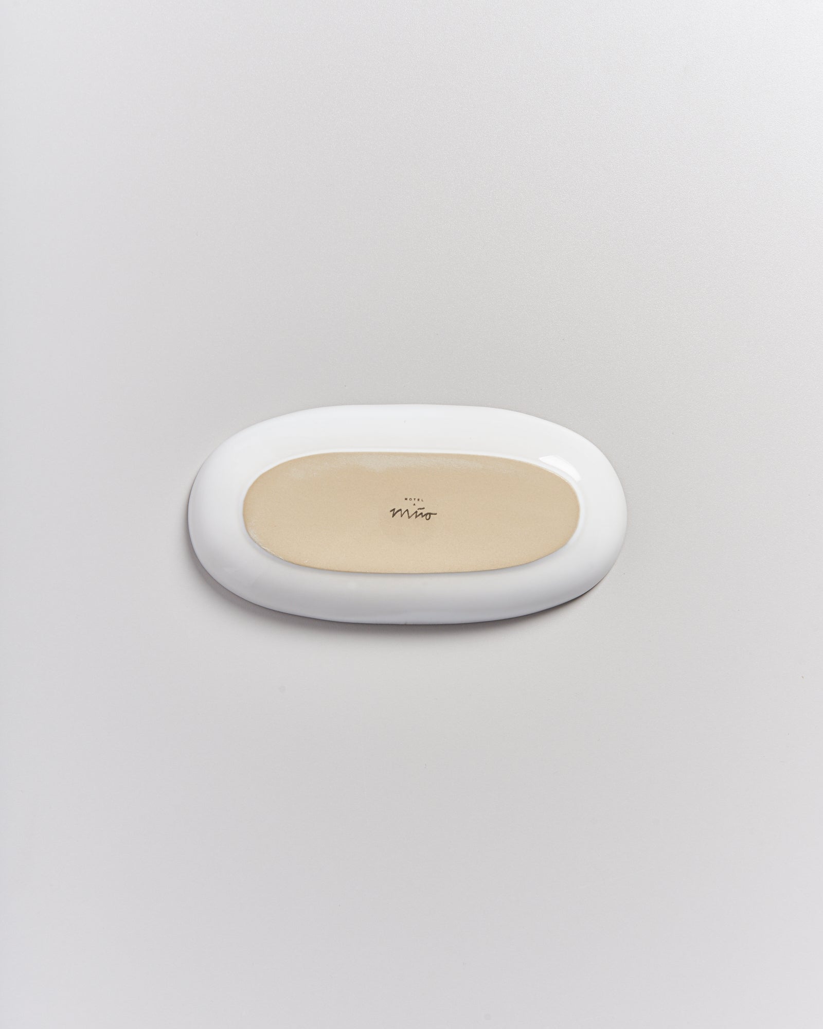 Weiße, ovale Seifenschale mit beiger Innenfläche auf hellem Hintergrund.