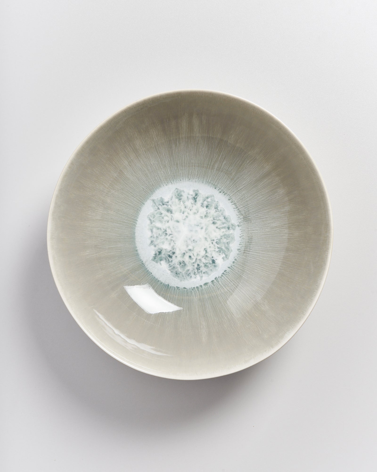 Keramikschale mit hellem, radialem Muster auf grauem Hintergrund.