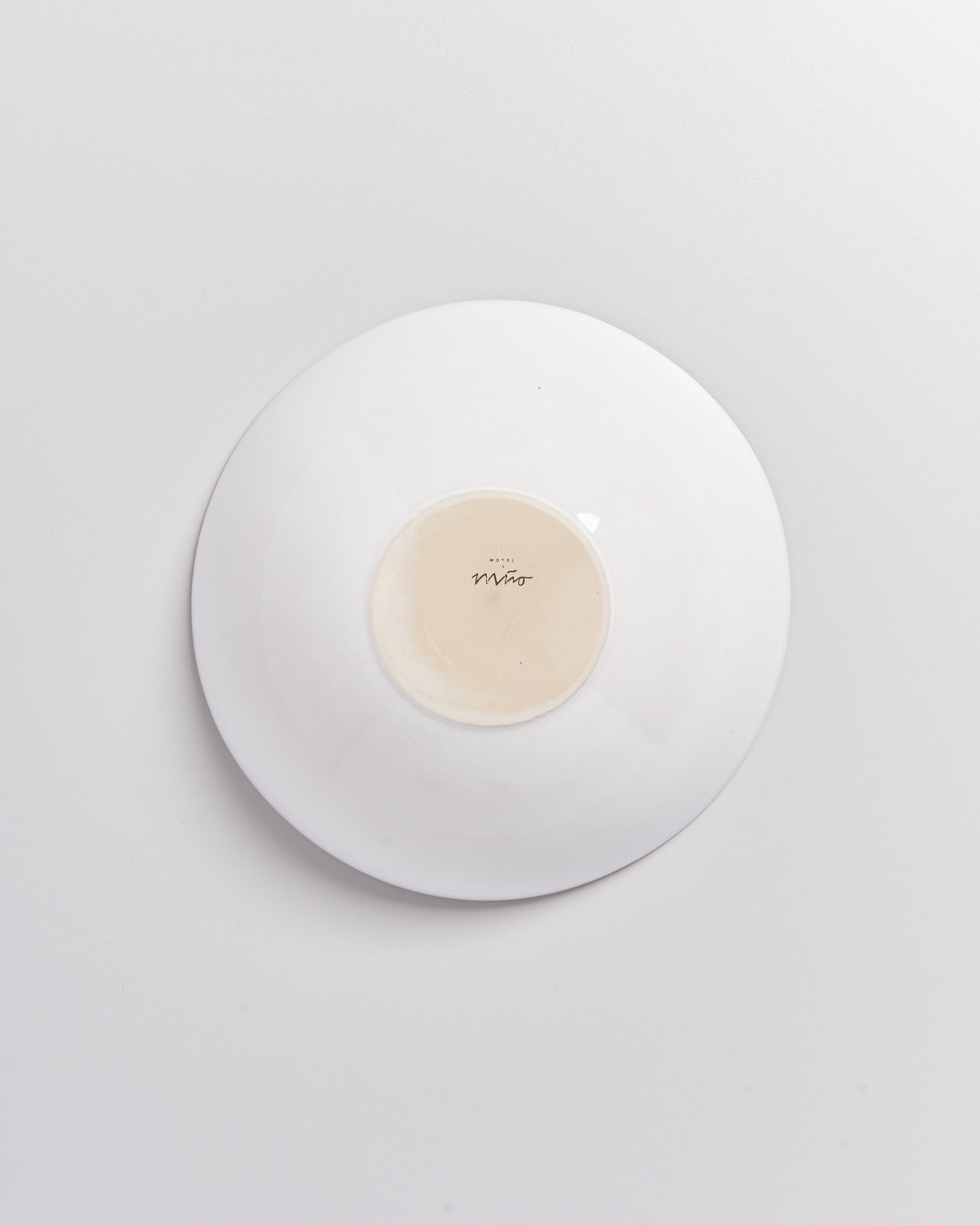 Weiße Schüssel auf einem hellgrauen Hintergrund, umgedreht mit der Aufschrift "Mino" auf der Unterseite.