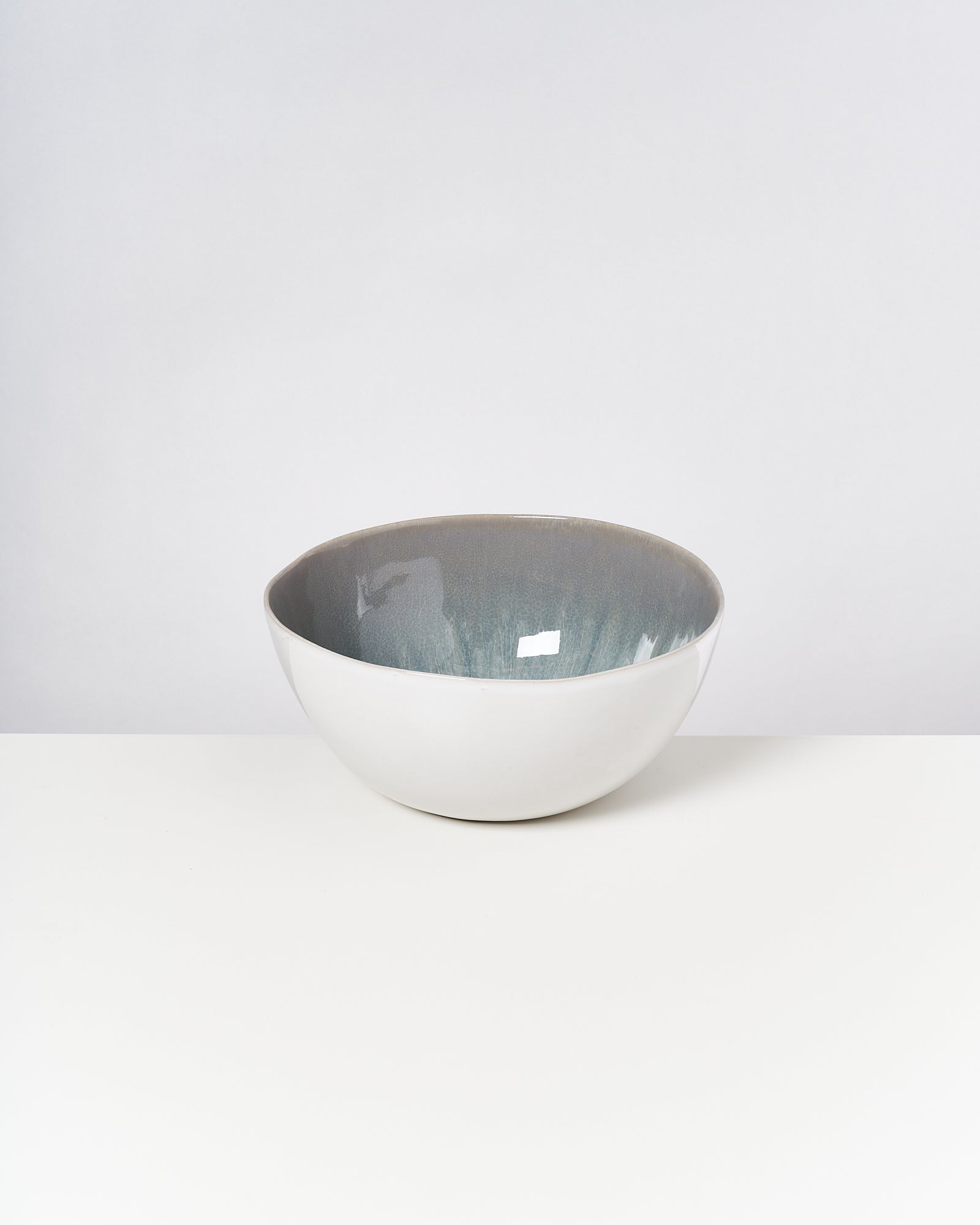 Weiße Keramikschale mit grauem Inneren steht vor neutralem Hintergrund auf weißem Tisch.