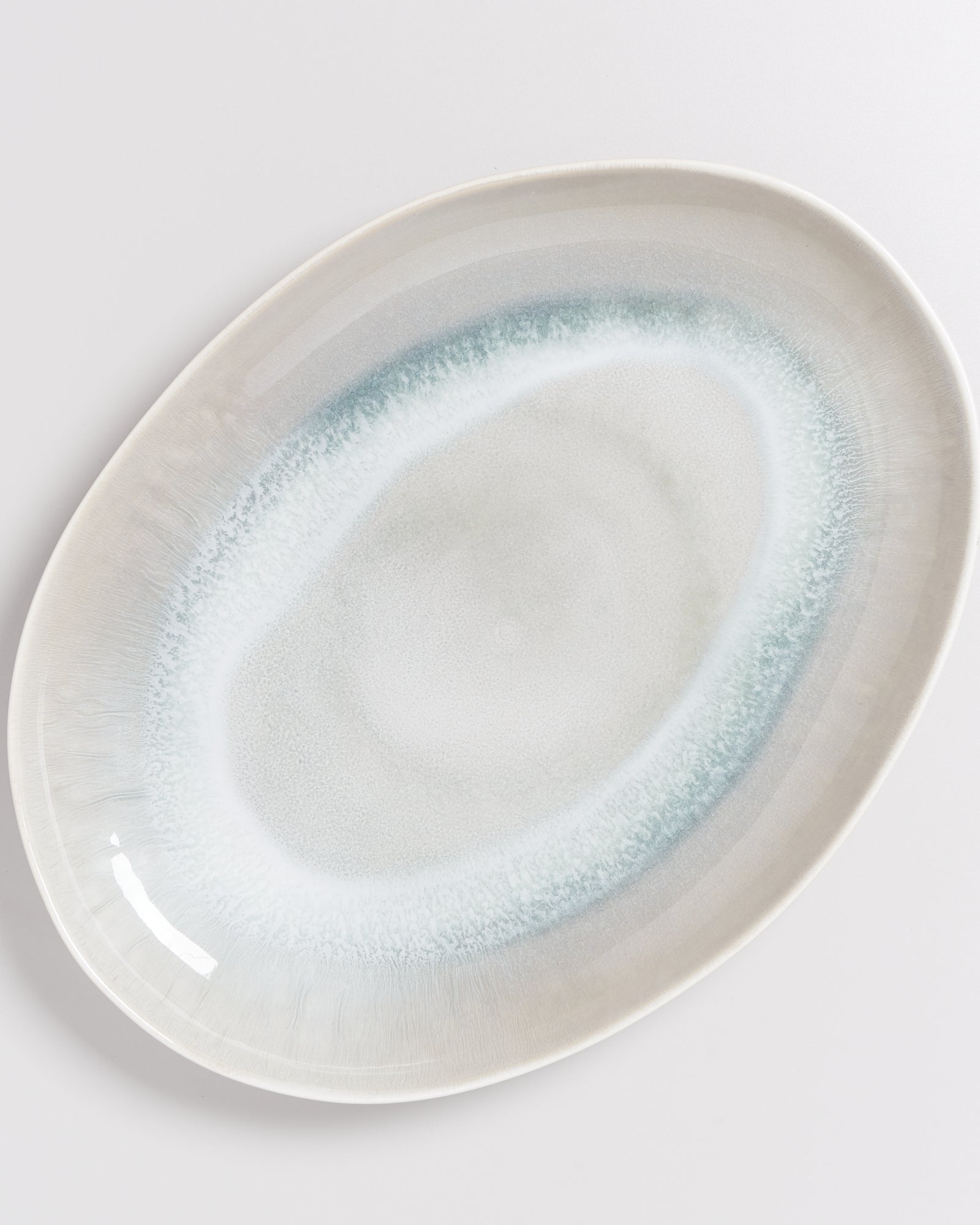 Ovaler Teller mit weiß-blauem Verlaufsmuster auf hellem Hintergrund.