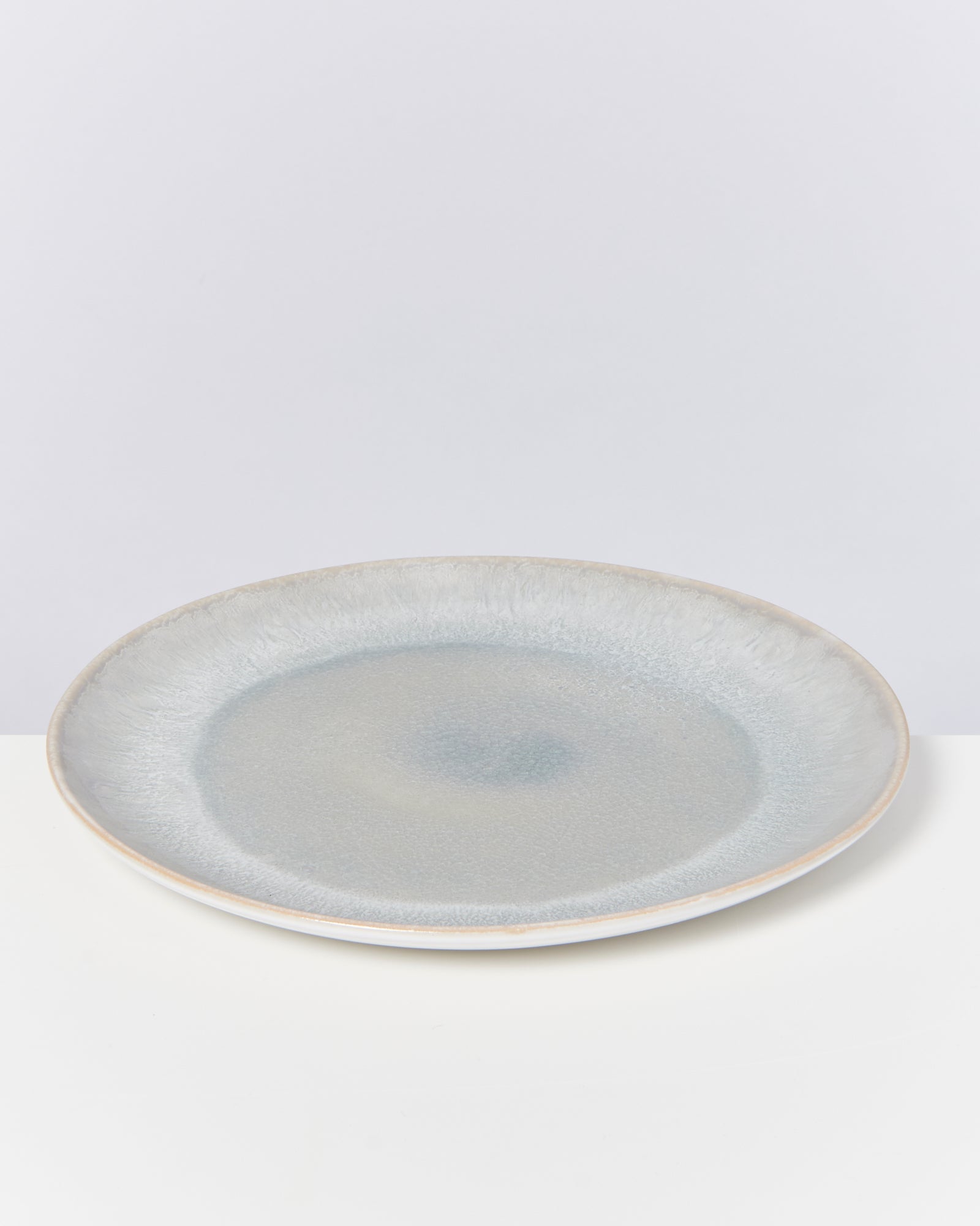 Keramikteller mit bläulichem Farbverlauf und texturierter Oberfläche auf weißem Hintergrund.