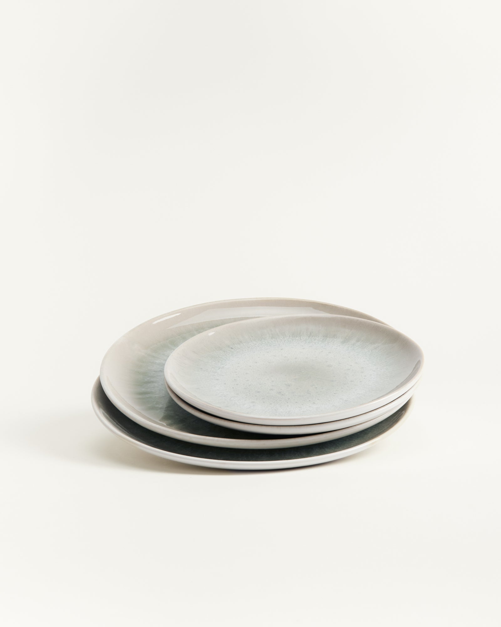 Ein Stapel aus drei übereinanderliegenden grauen Tellern auf einem weißen Hintergrund.