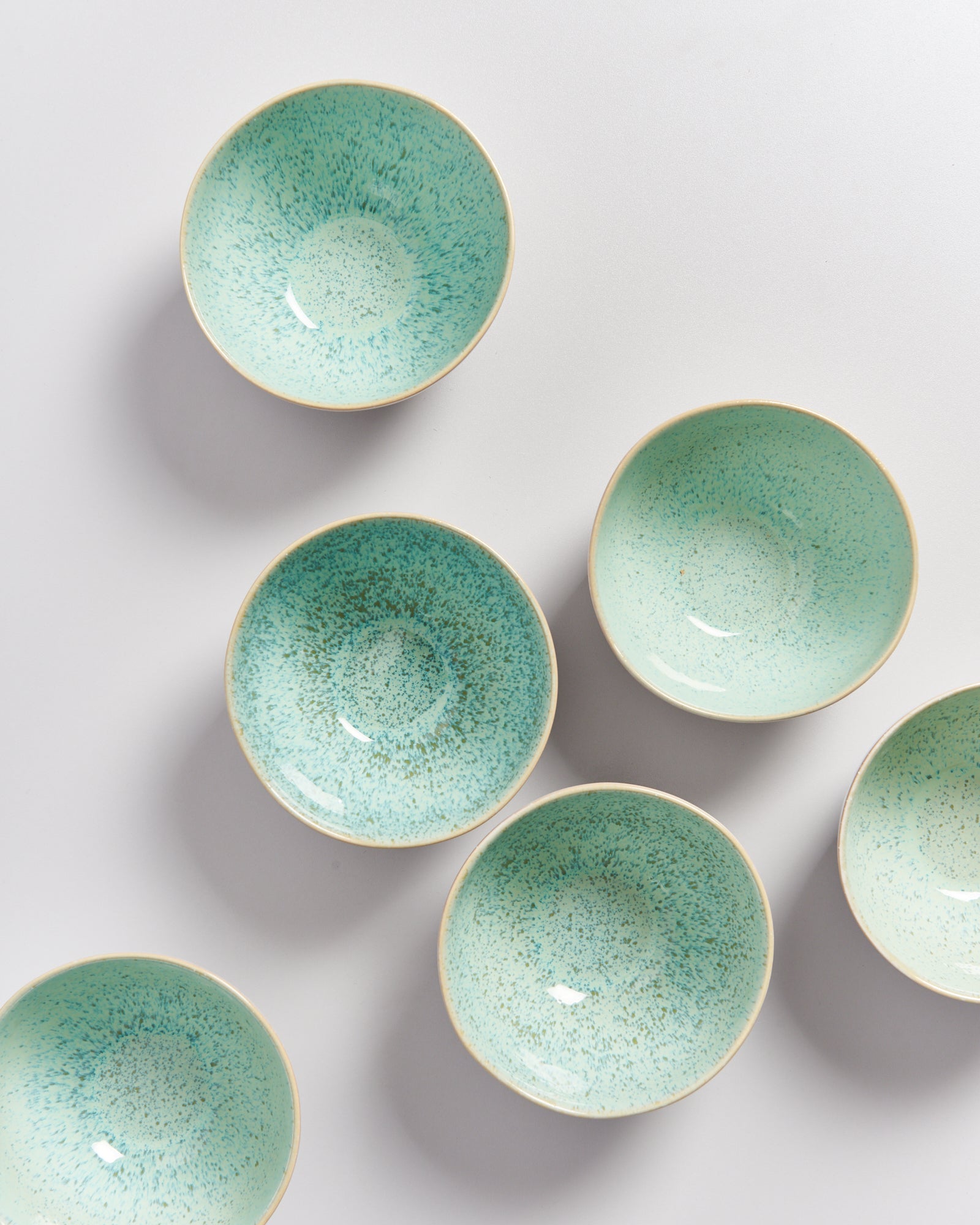 Sechs türkisfarbene Schalen mit gesprenkeltem Muster auf weißem Hintergrund.