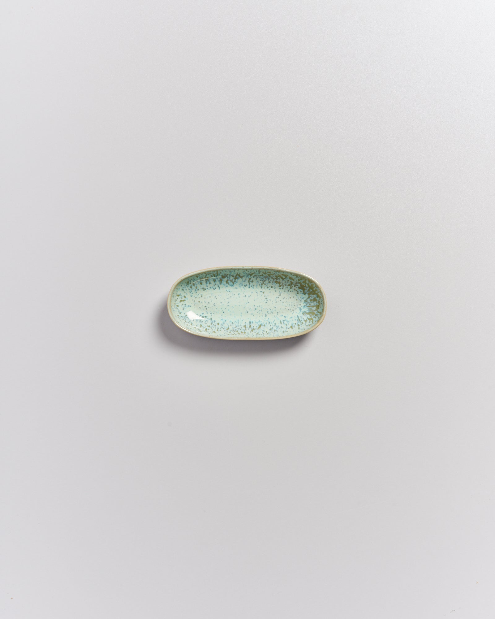 Kleiner, hellblauer, rechteckiger Teller mit Sprenkeln auf hellem Hintergrund.