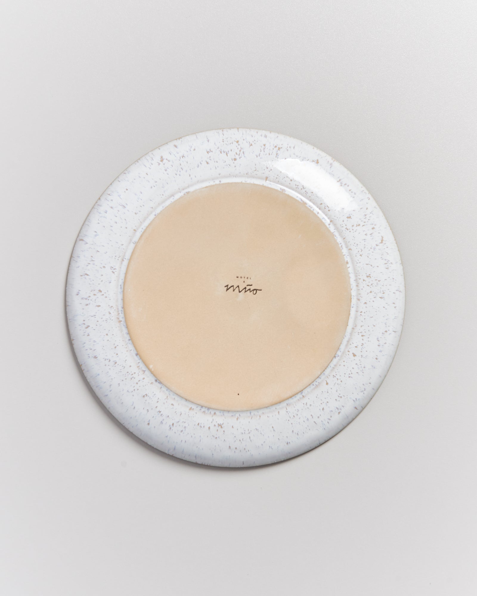 Rückseite eines Keramiktellers mit beige Mitte und gesprenkeltem Rand; Aufschrift "Hotel Miro" in der Mitte.