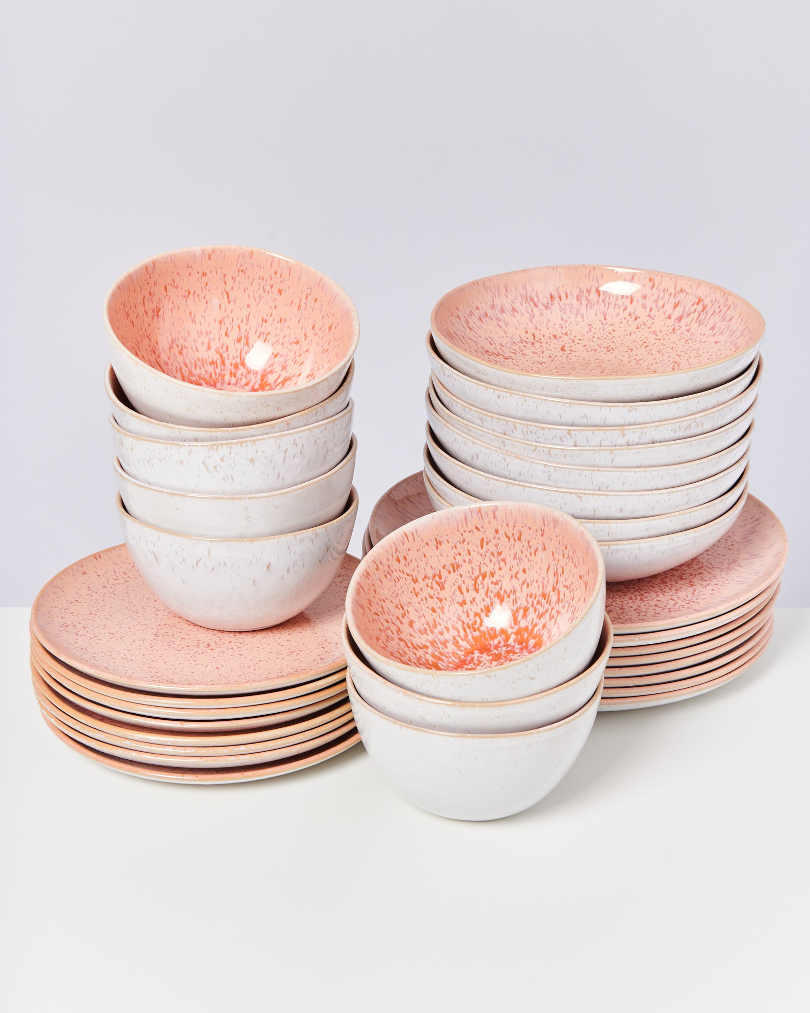 Stapel von rosa und weißen Schüsseln und Tellern auf einem Tisch.