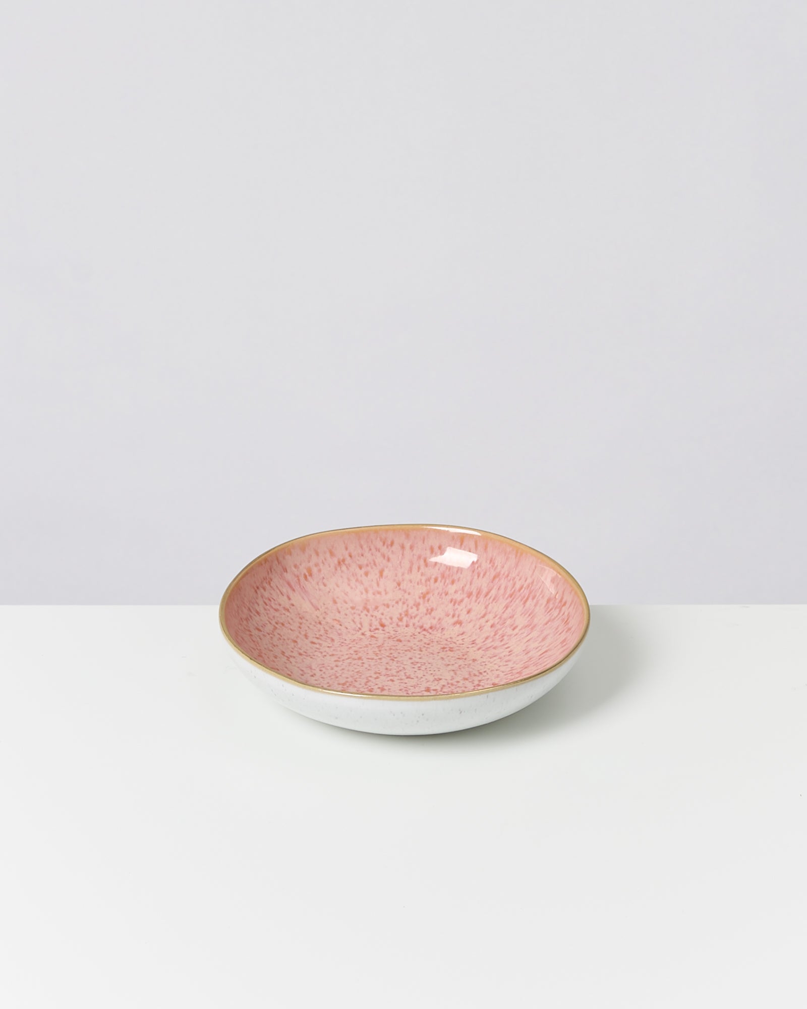Rosa Schale mit Sprenkeln auf weißem Untergrund vor neutralem Hintergrund.