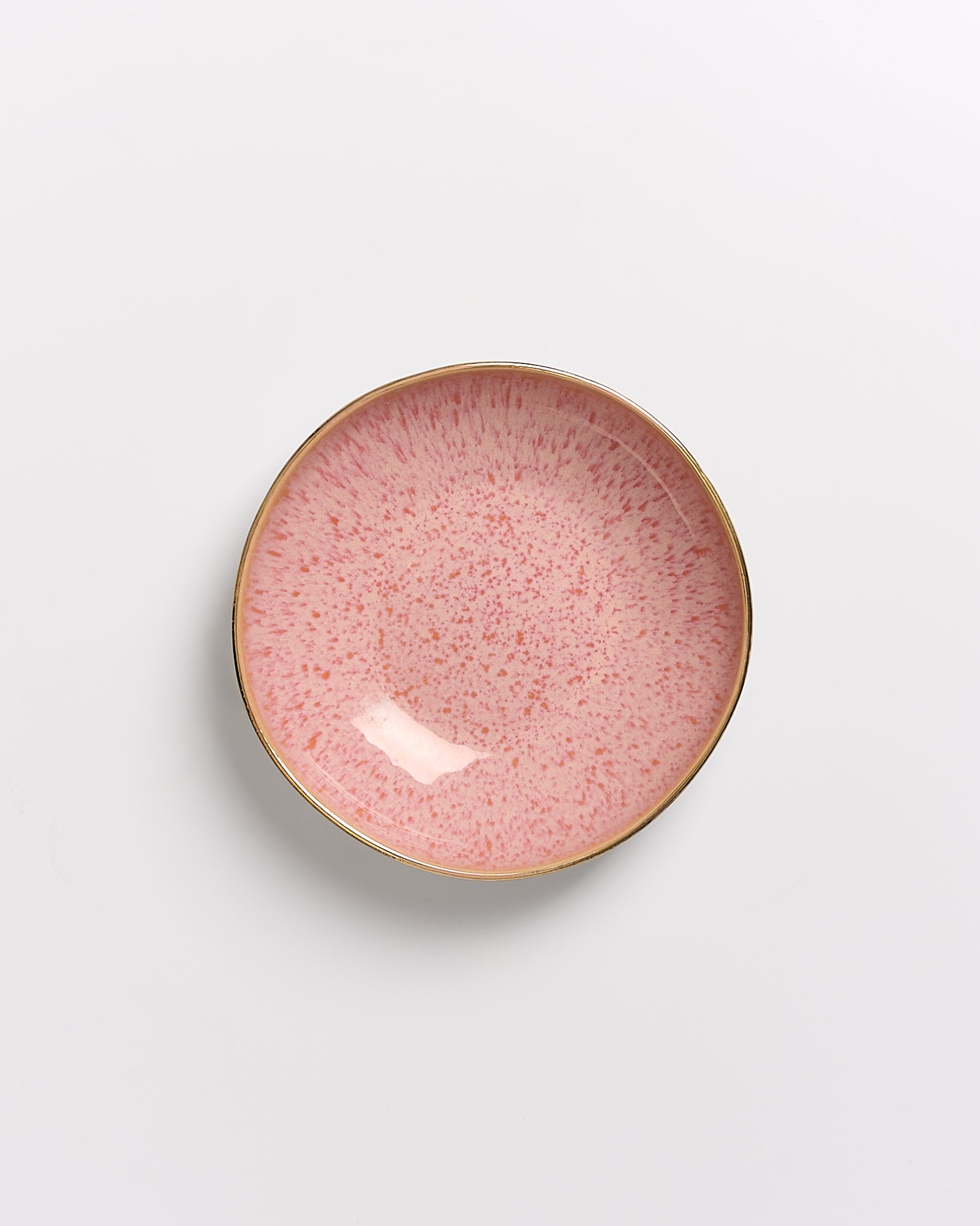 Runder Teller mit rosa Sprenkeln und einem goldenen Rand auf weißem Hintergrund.