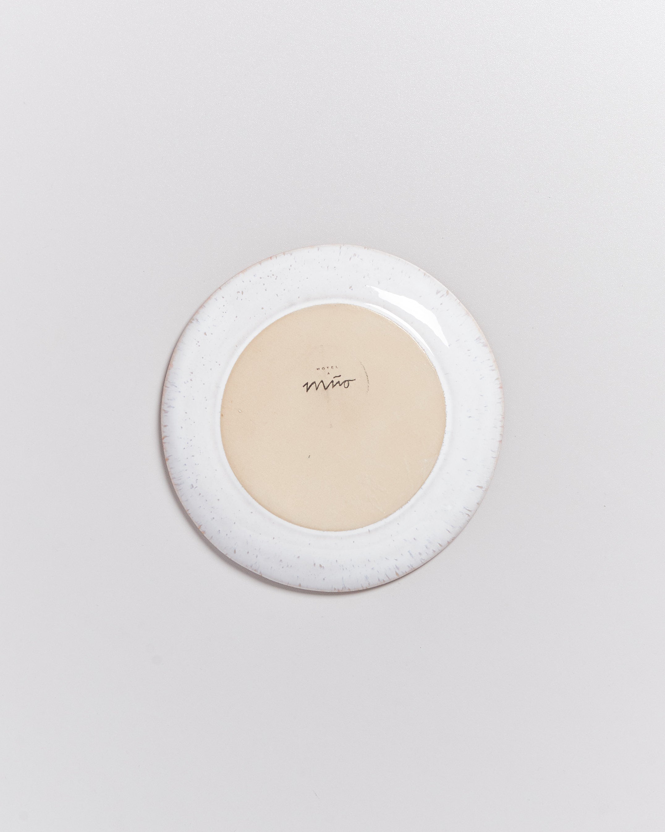 Rückseite eines weißen Tellers mit einem beigen Zentrum und einem Logo darauf.